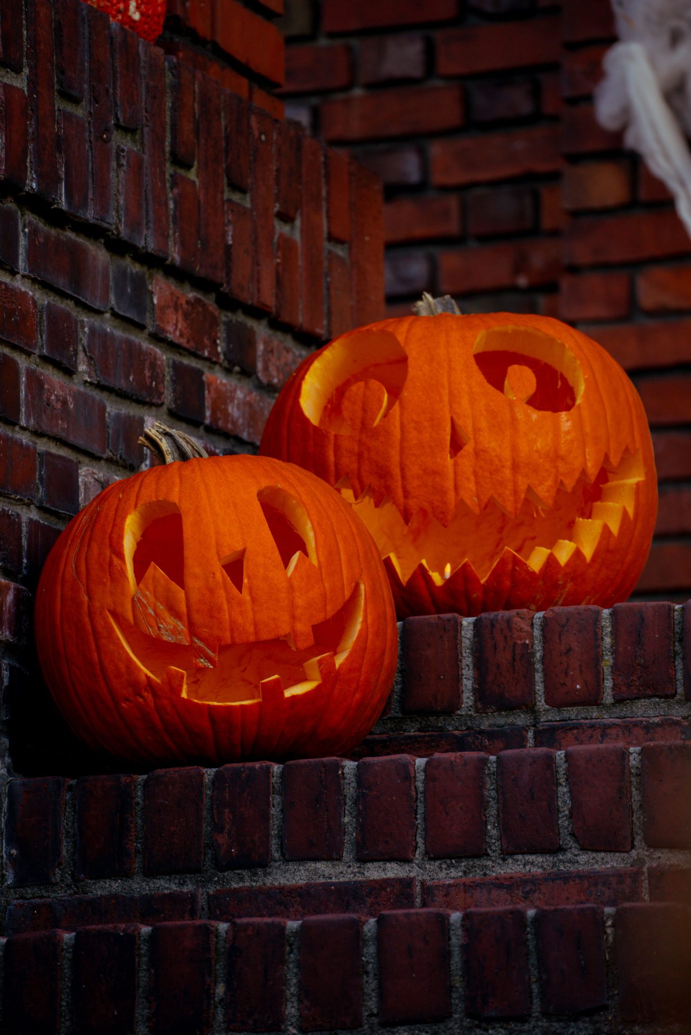 Two carved Jack-o'-lanterns on brick stairs create a spooky Halloween atmosphere.