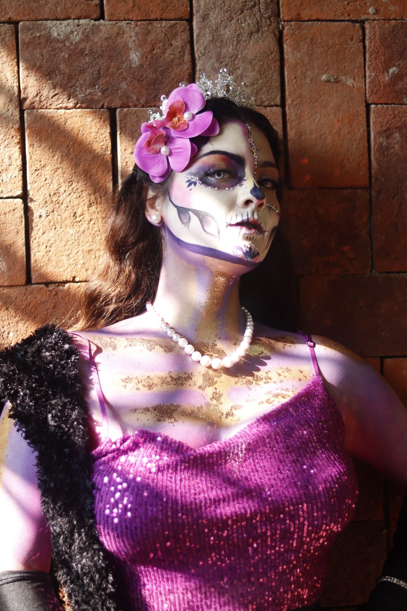 Vibrant Day of the Dead makeup with purple dress and floral crown.