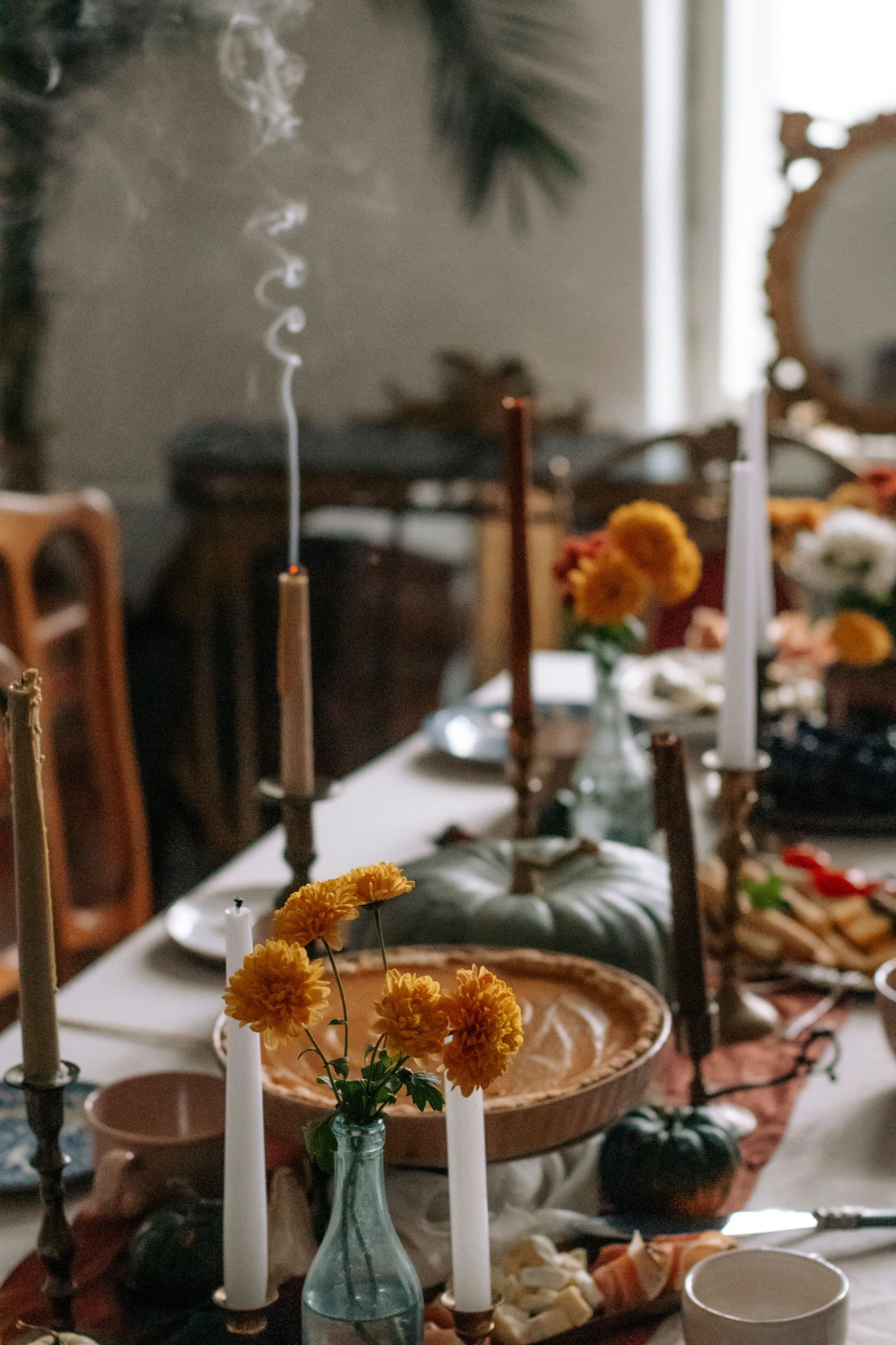 Warm and inviting autumn table setting featuring pumpkins, candles, and fall flowers.