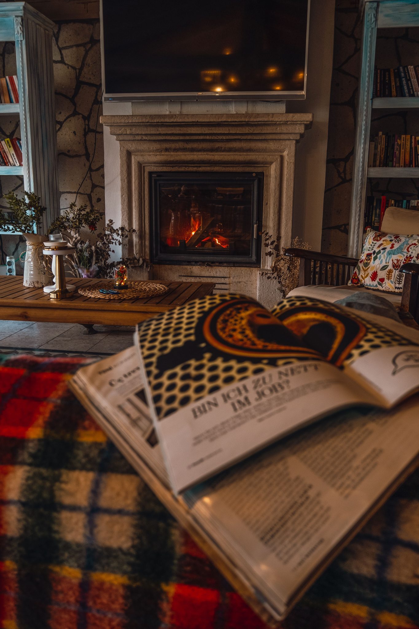 Warm and inviting living room featuring a fireplace, open book, and colorful decor for a relaxing ambiance.