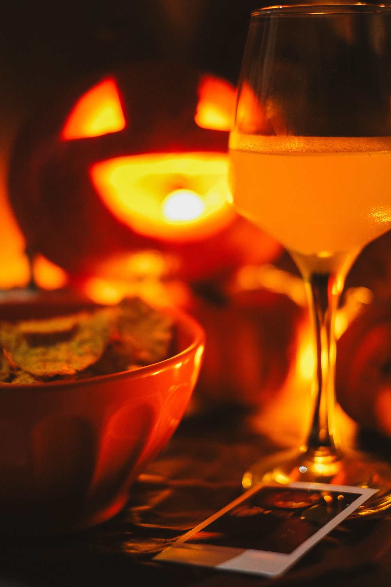 Warm autumn scene featuring a jack-o-lantern, cider glass, and chips, perfect for Halloween ambiance.