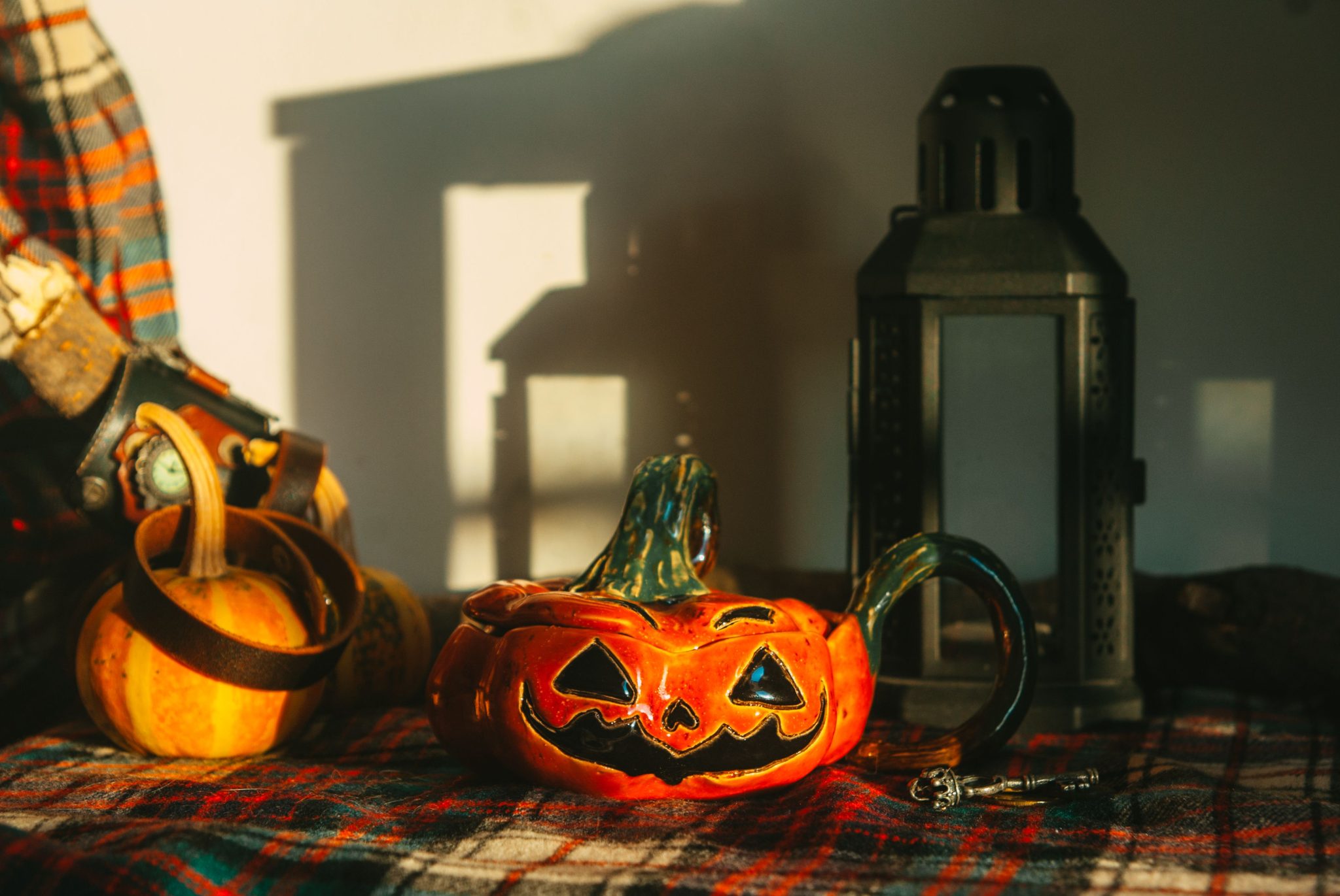 Warm autumn scene with Jack-o'-lantern, pumpkins, and lantern creating a cozy indoor Halloween ambiance.