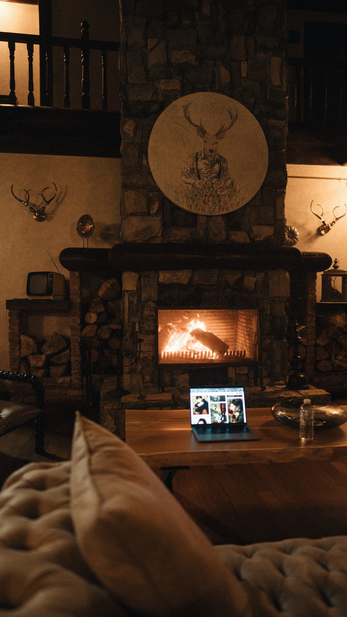 Warm cabin interior with a lit fireplace and tablet, creating a modern rustic atmosphere.