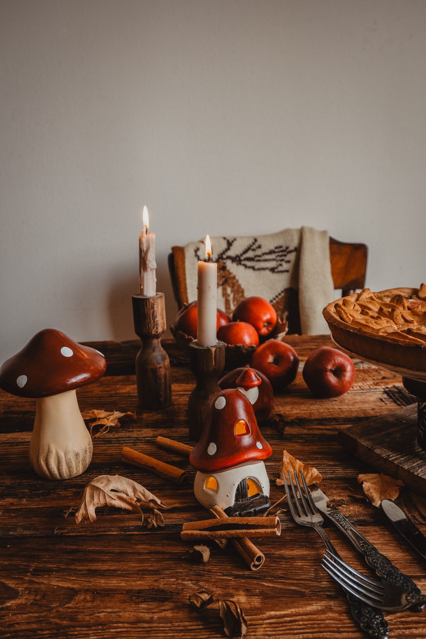 Warm fall table setting with candles, apples, and rustic decor. Perfect for cozy interiors.