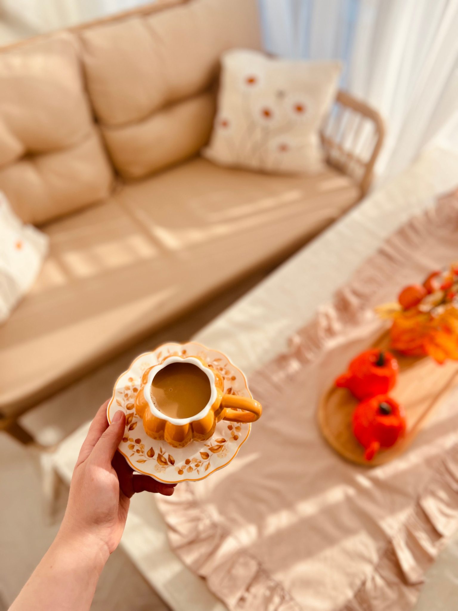 Warm indoor scene with coffee, pumpkins, and cozy autumn decor.