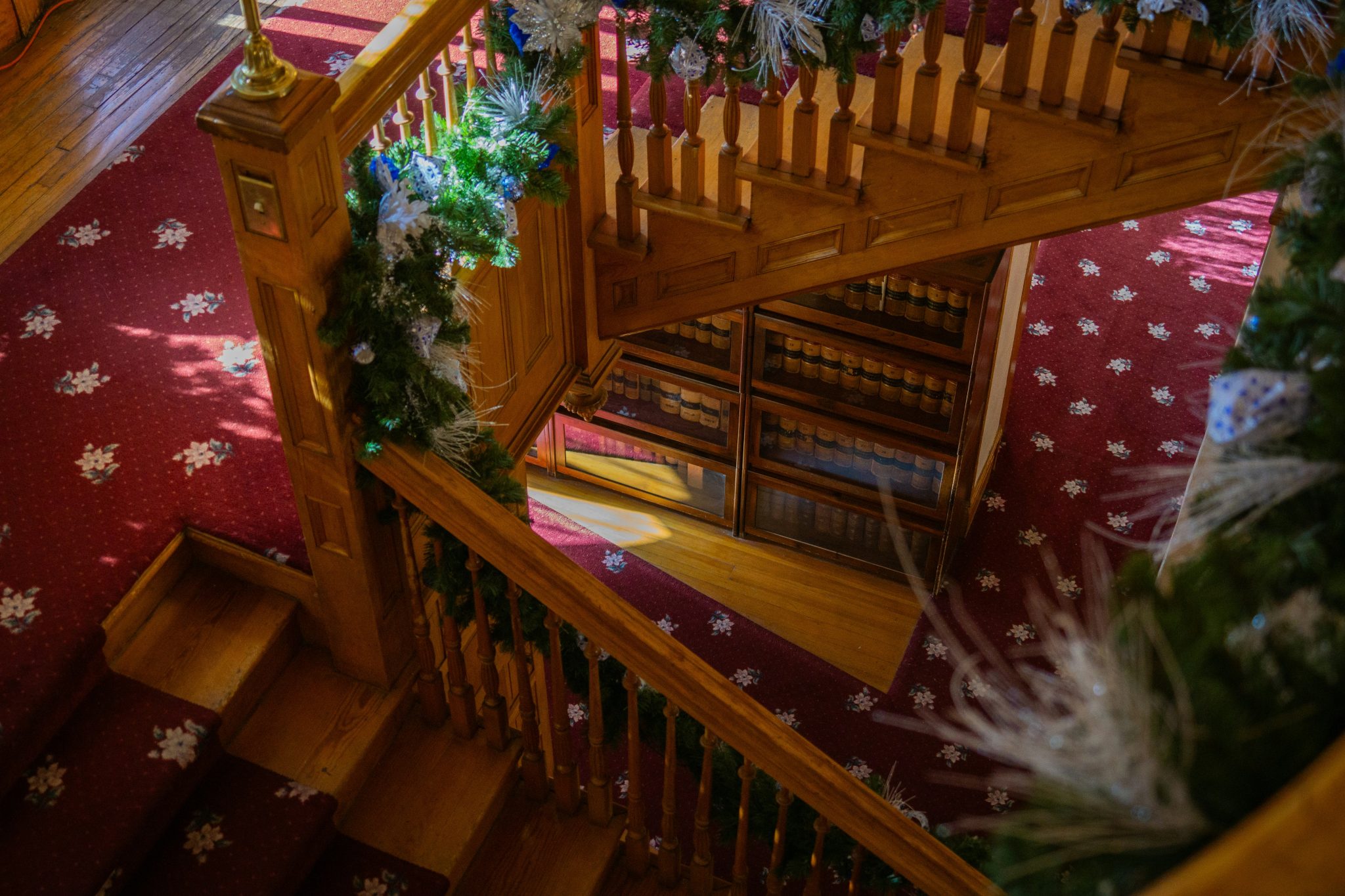 Wooden staircase decorated with festive greenery and lights.