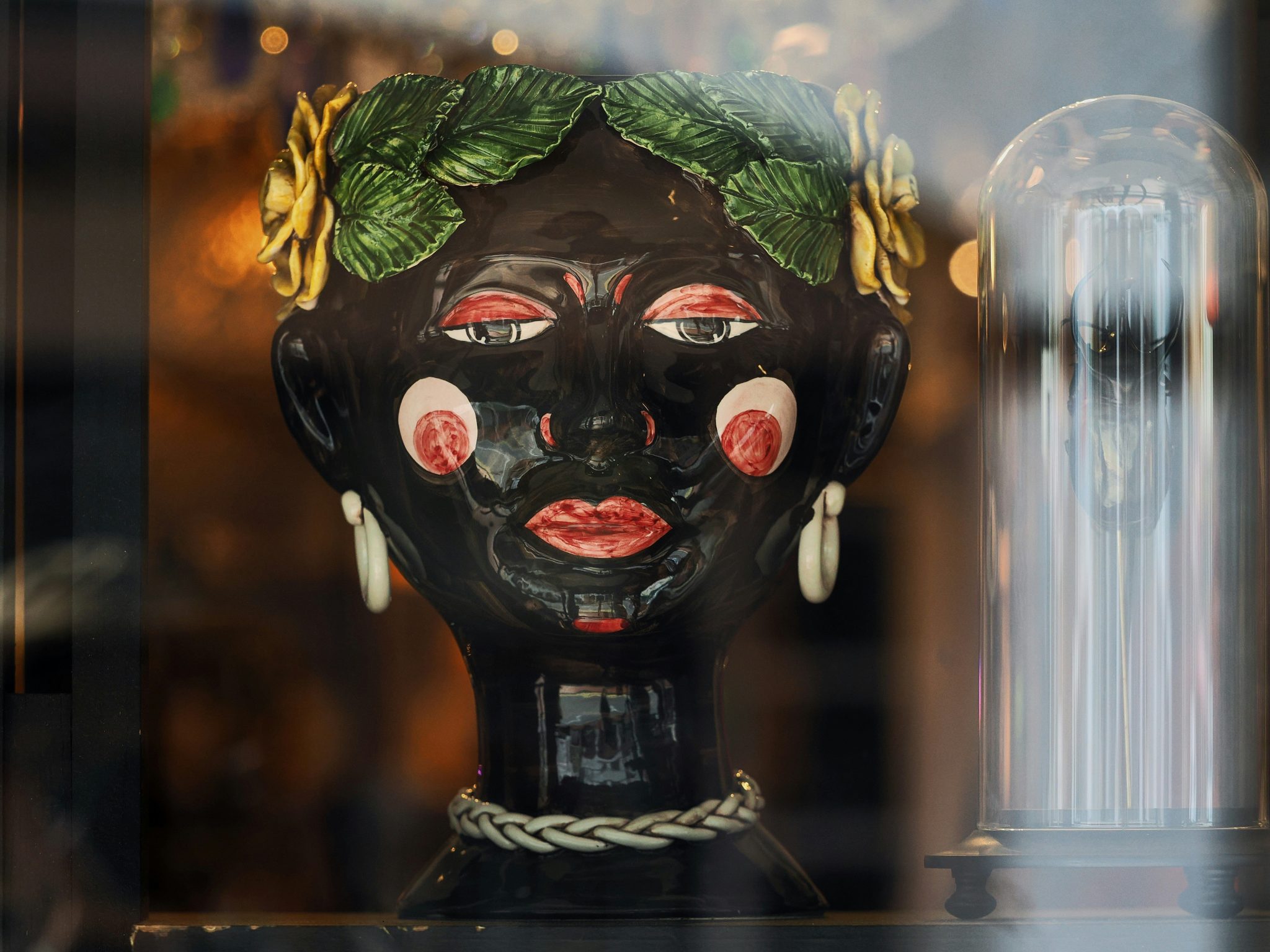 A ceramic head planter with green leaves and yellow flowers in a shop window