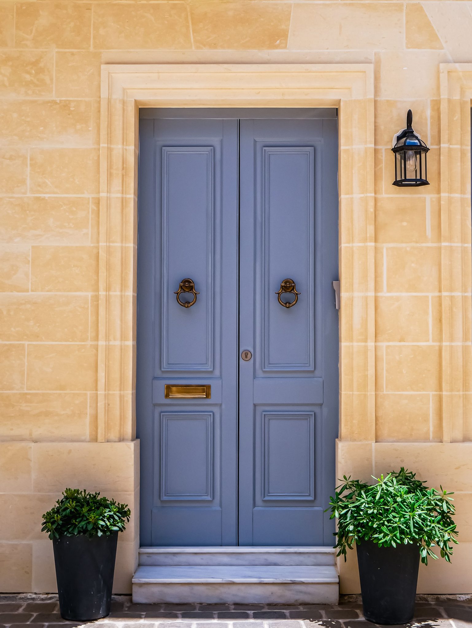 A charming blue door set in a limestone facade, symbolizing classic Mediterranean architecture.