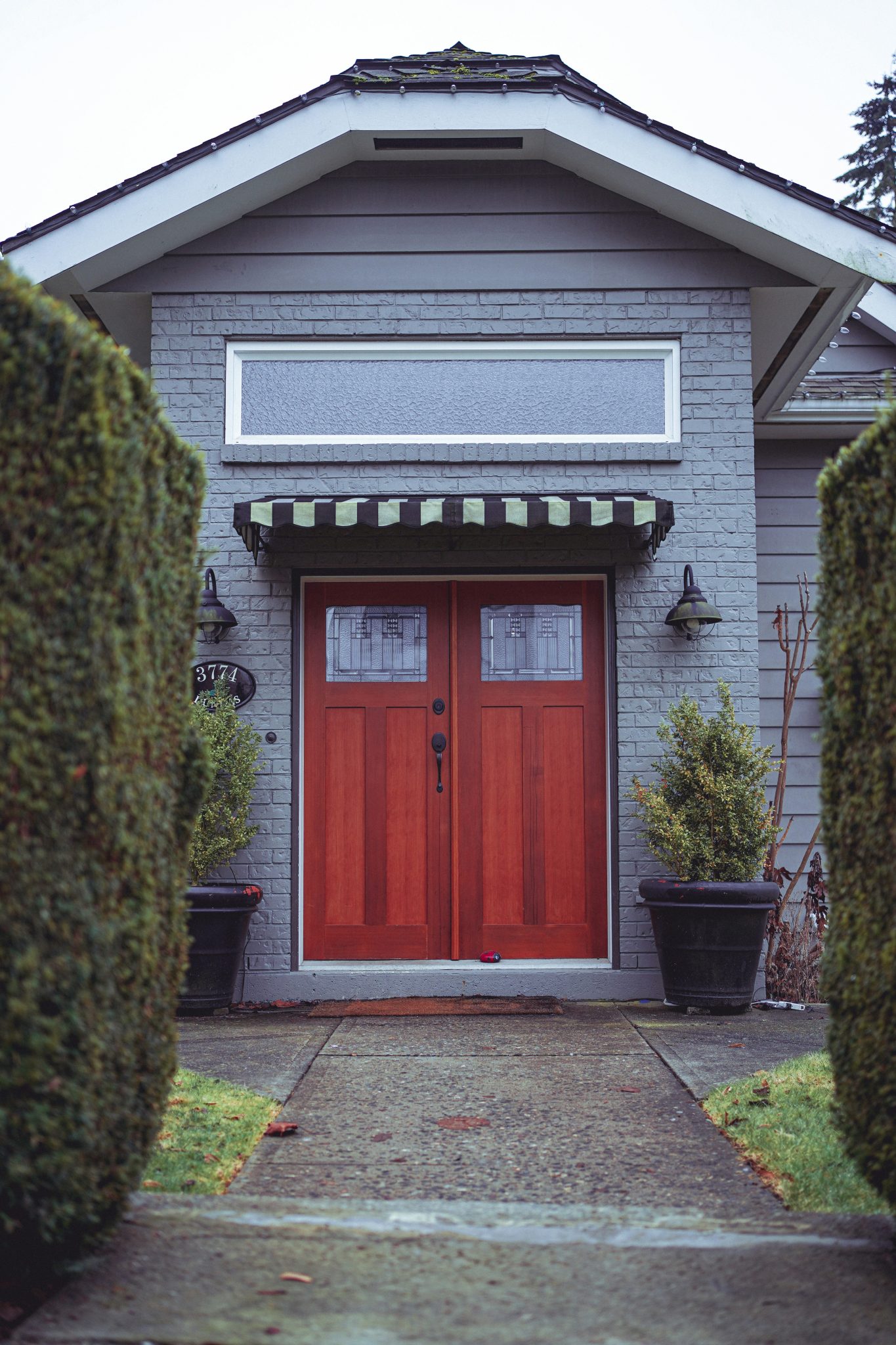 a red door is in front of a gray house