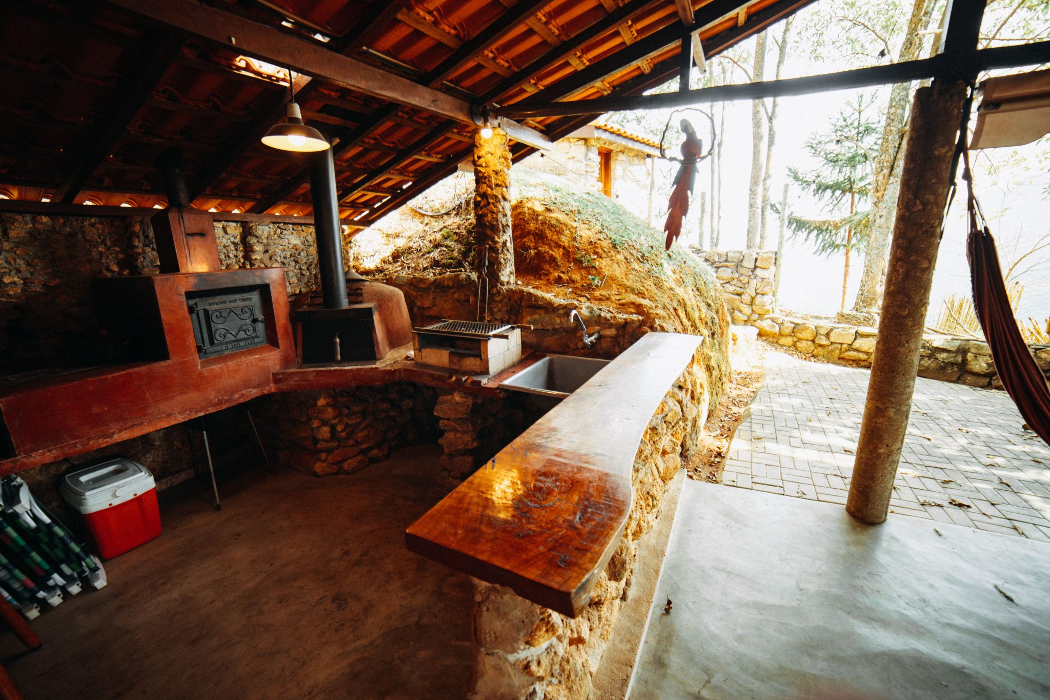 A rustic outdoor kitchen featuring a traditional wood-fired stone oven and wooden countertop.