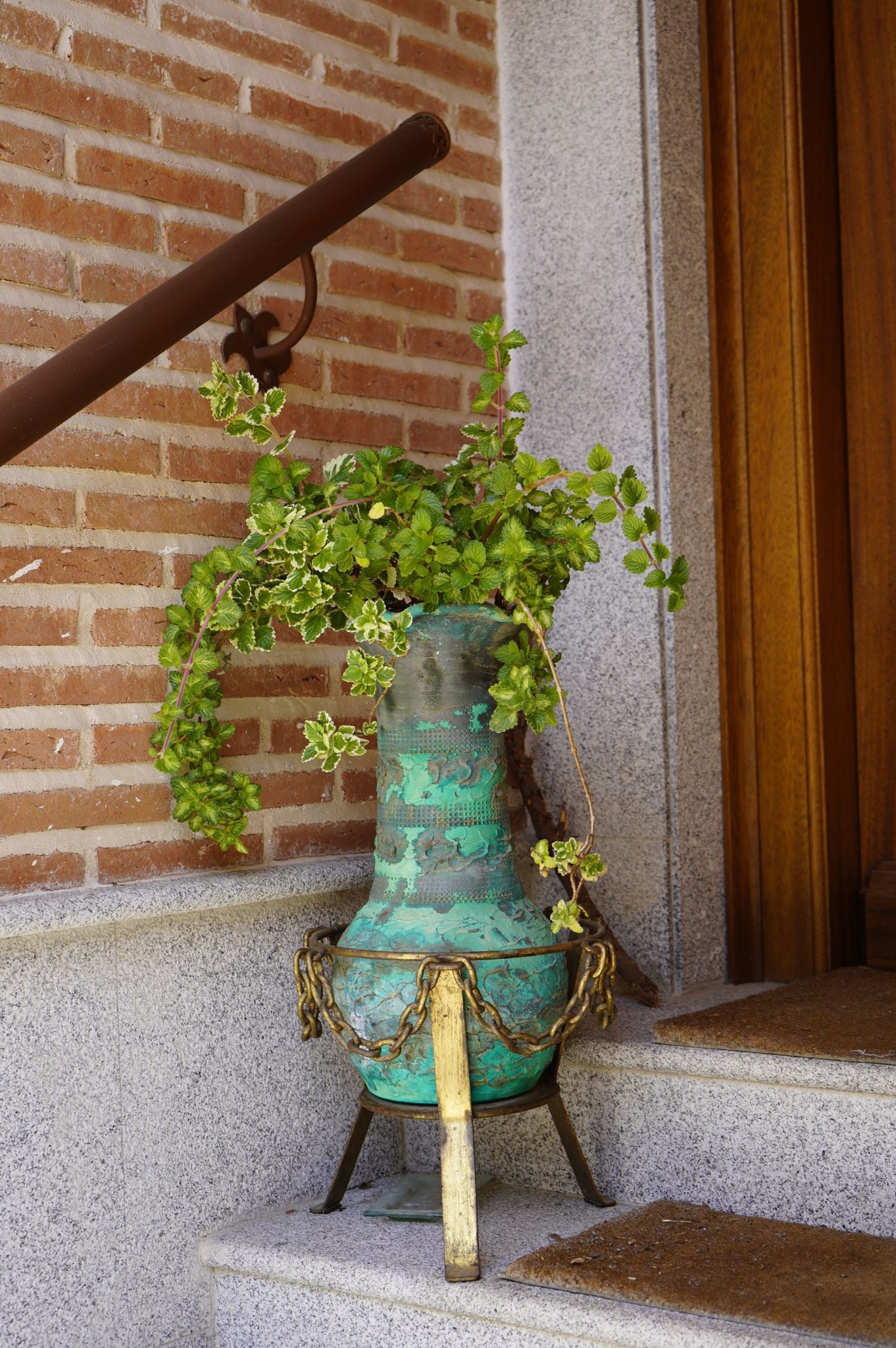 A rustic terracotta pot with lush greenery on a brick staircase, ideal for outdoor decor.