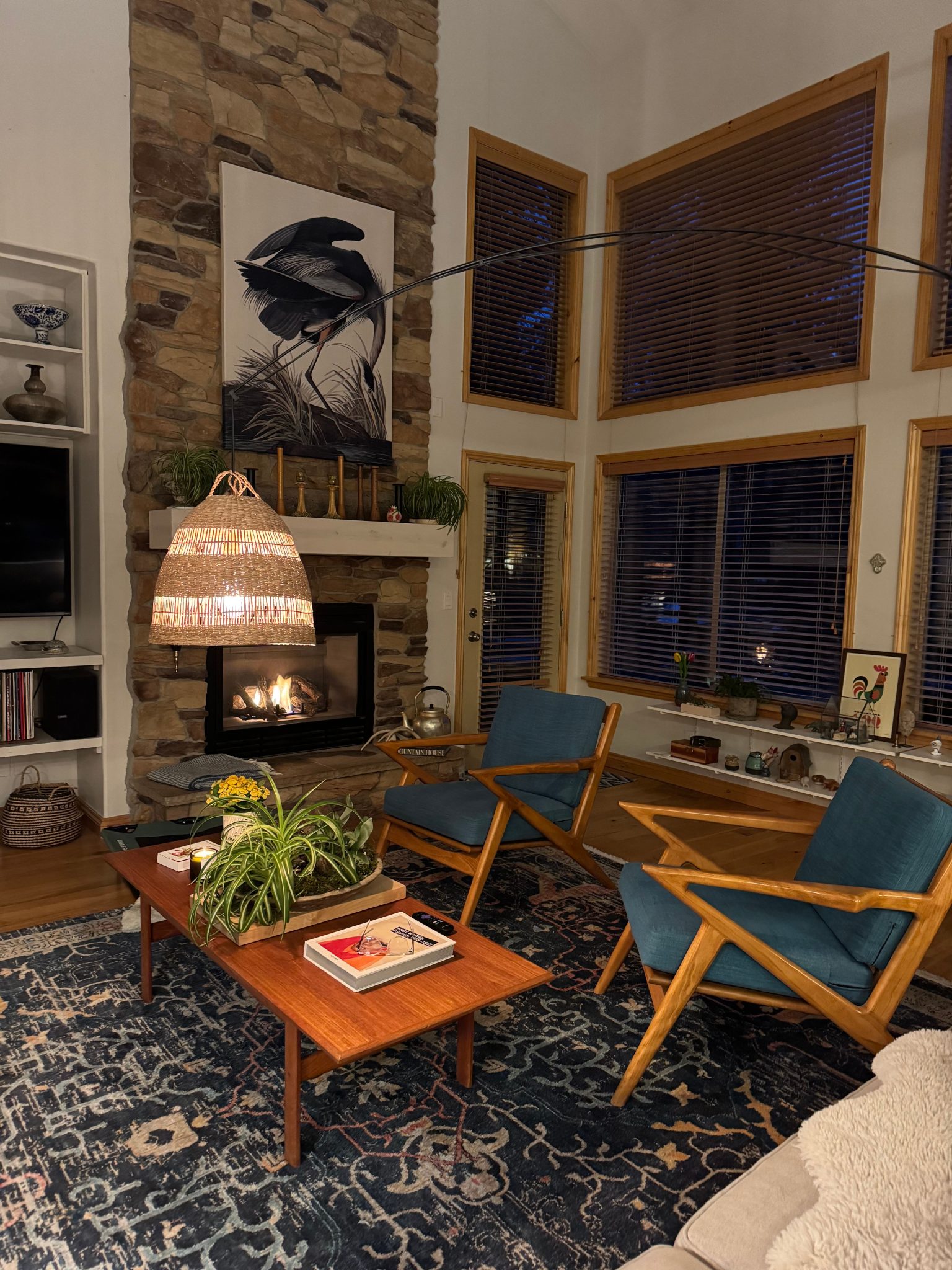A warm, stylish living room featuring a stone fireplace, modern chairs, and unique decor.