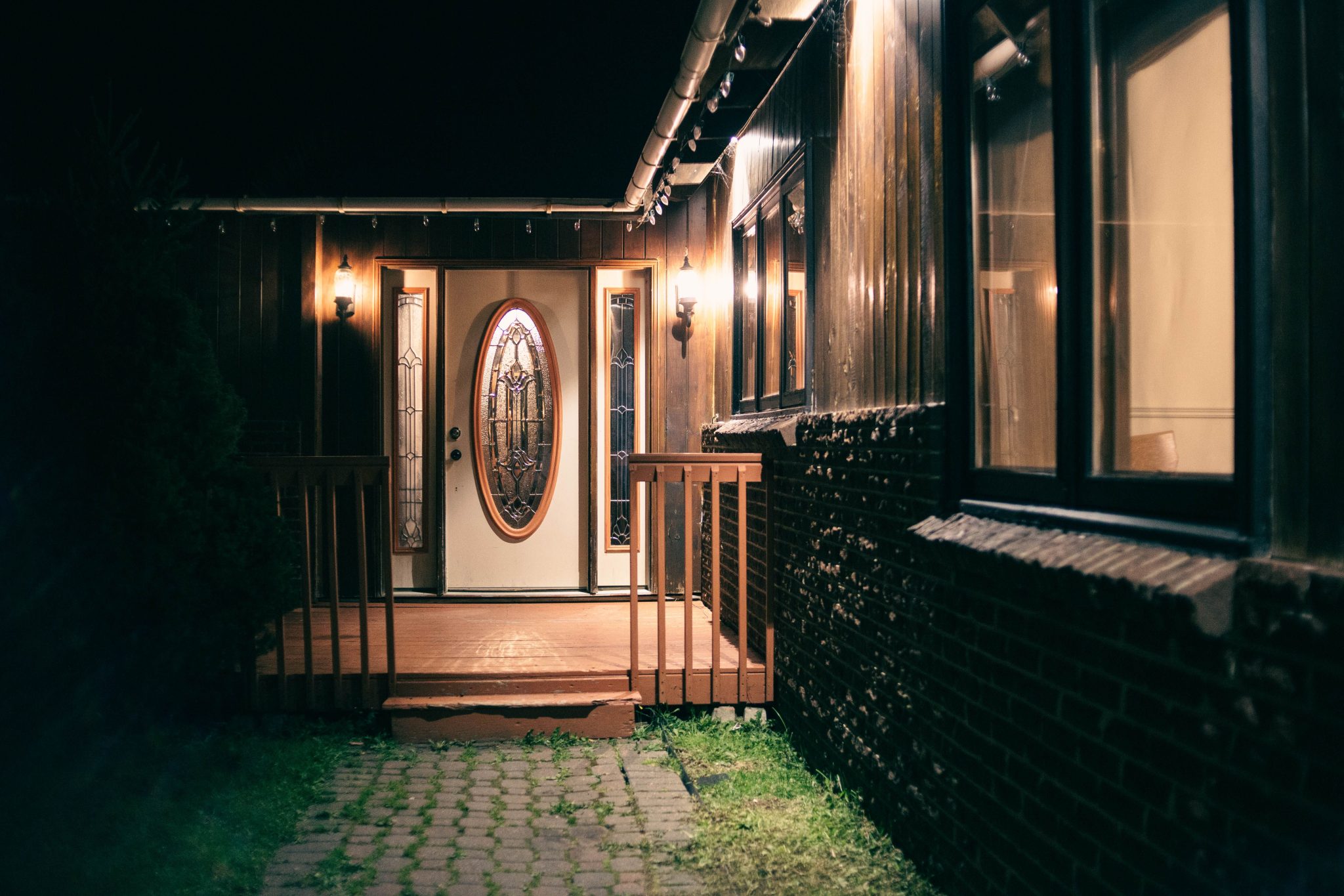 A warmly lit house entrance with decorative glass doors and glowing lantern lights at night.