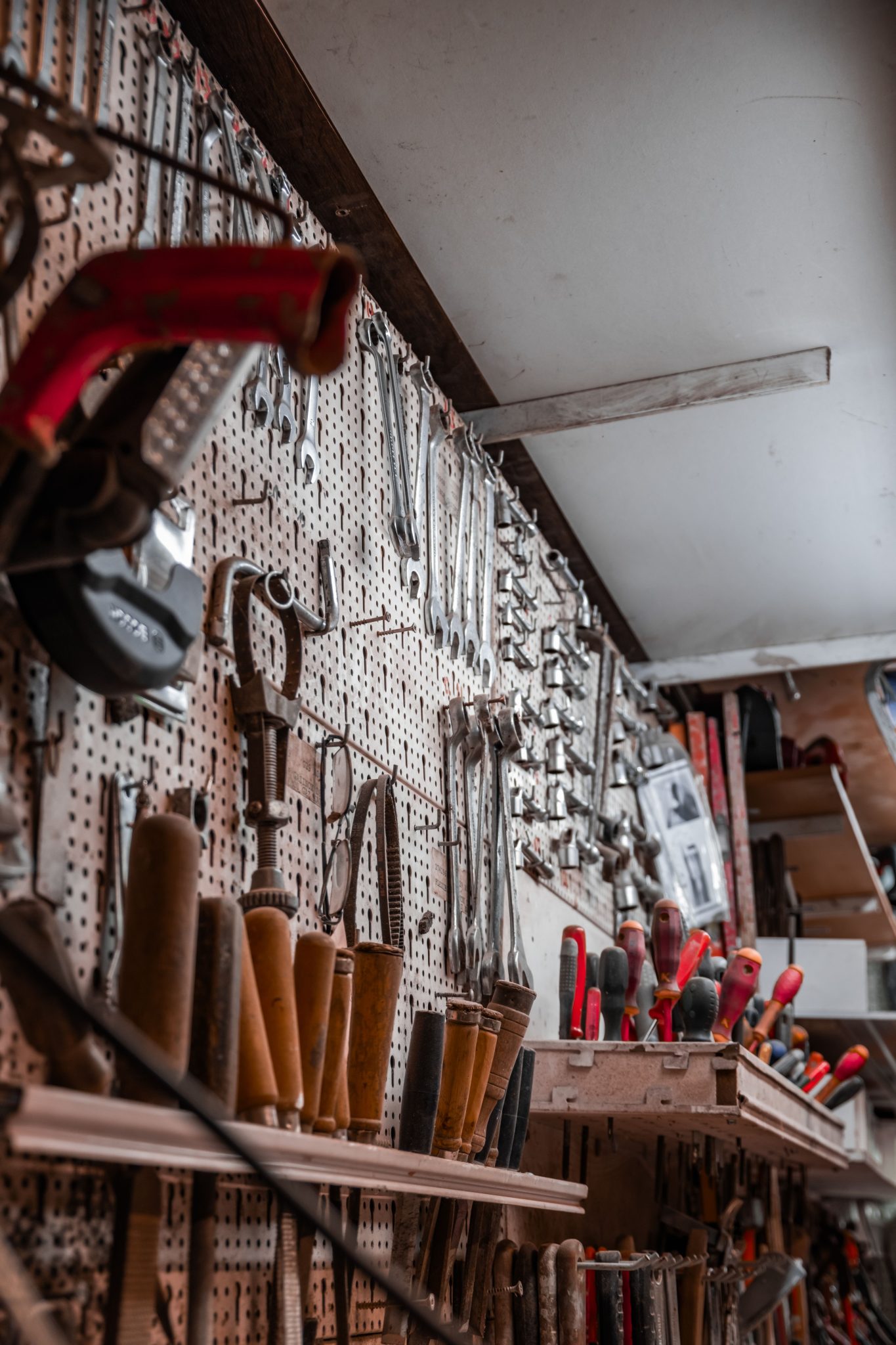 A workshop wall filled with various tools hanging for easy access and organization.
