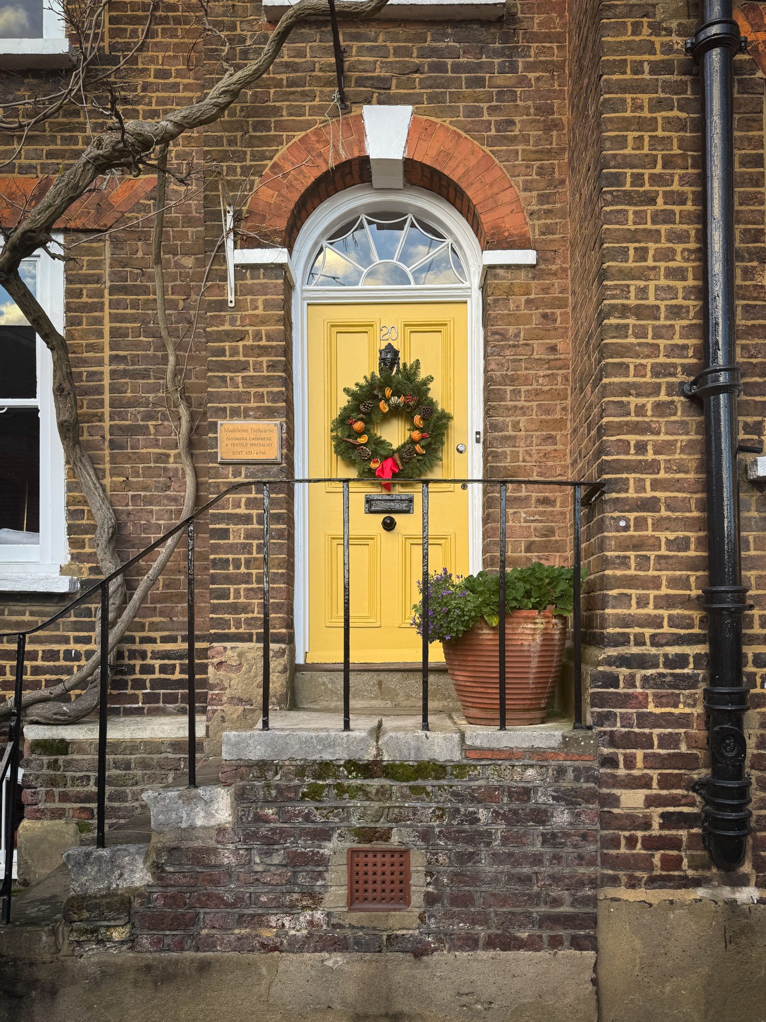 Brick house with yellow door and holiday wreath in Hampstead, London.