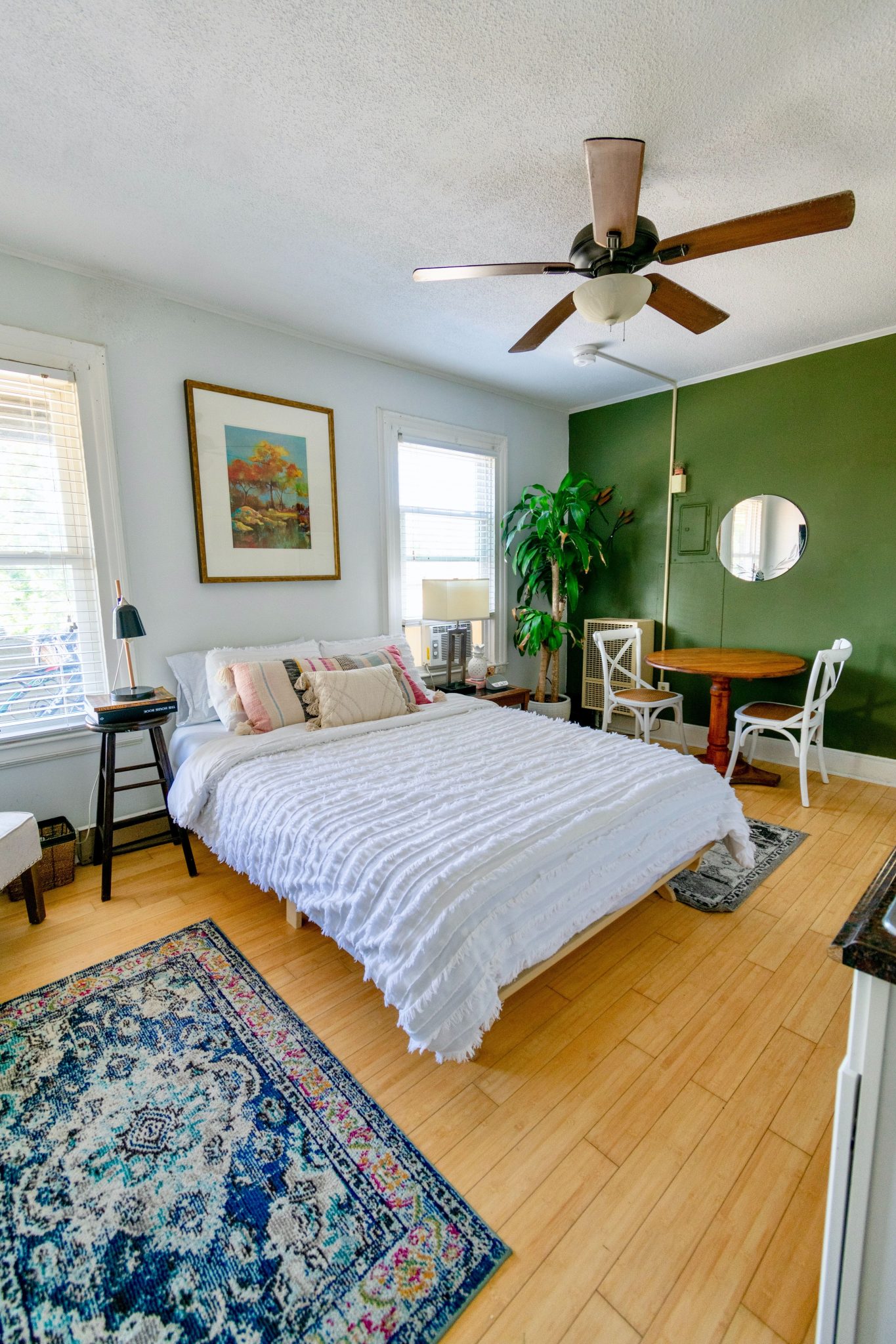 Bright bedroom with a green accent wall, wood flooring, and modern decor.