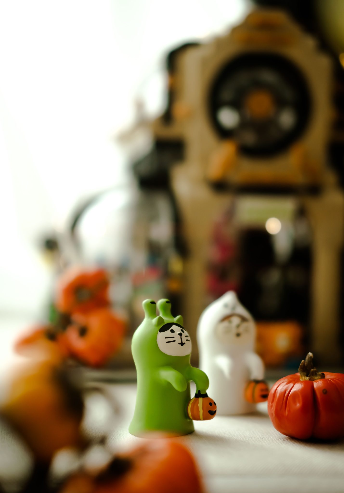 Charming Halloween figurines holding pumpkins on display indoors with soft focus.
