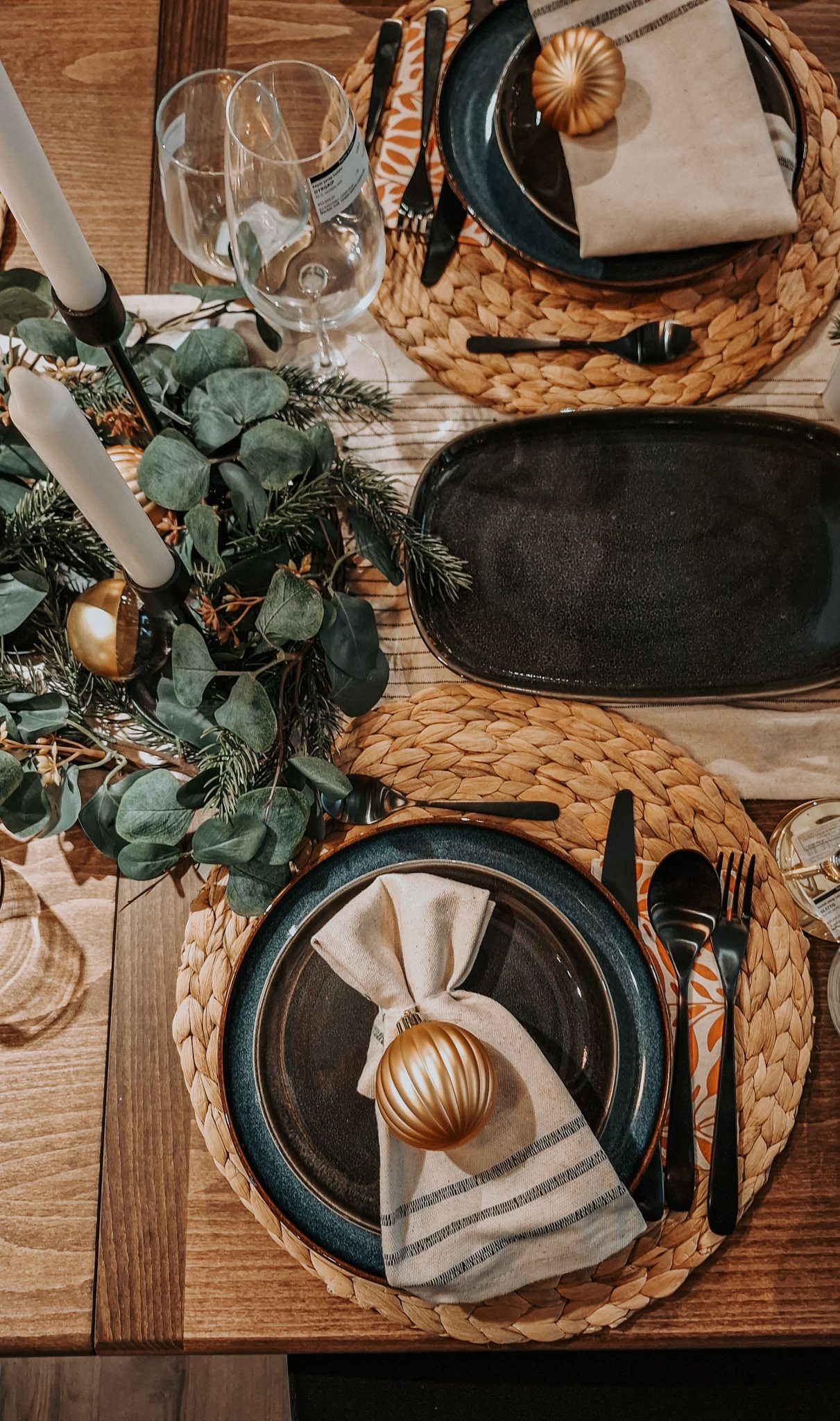 Charming holiday table setup with candles and greenery for a festive dinner.