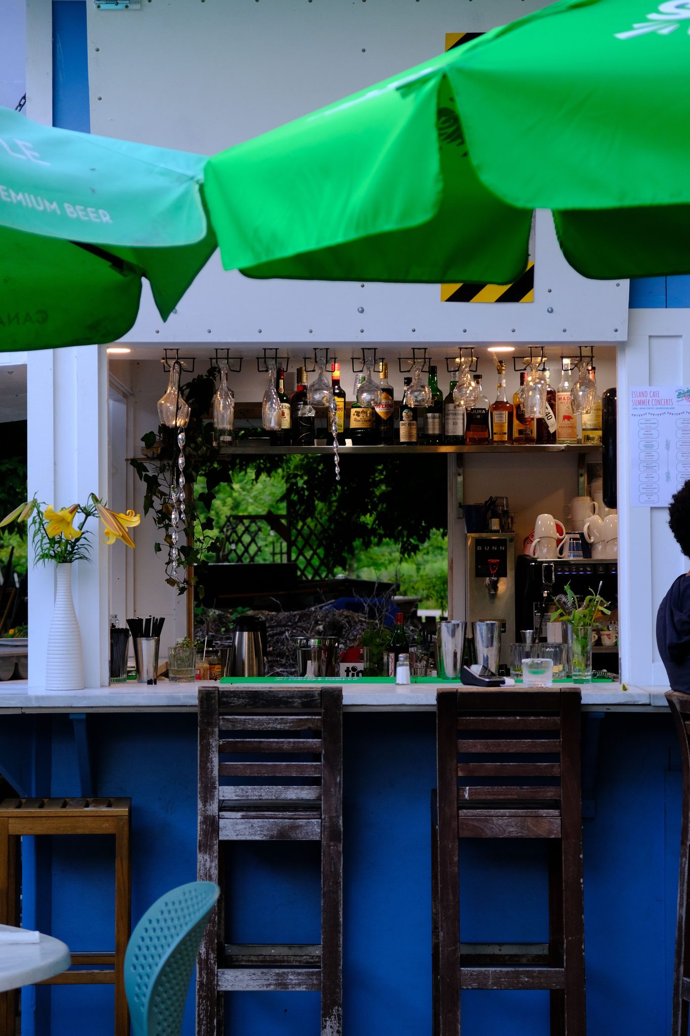 Charming outdoor bar in Ontario featuring vibrant green umbrellas and rustic wooden chairs.