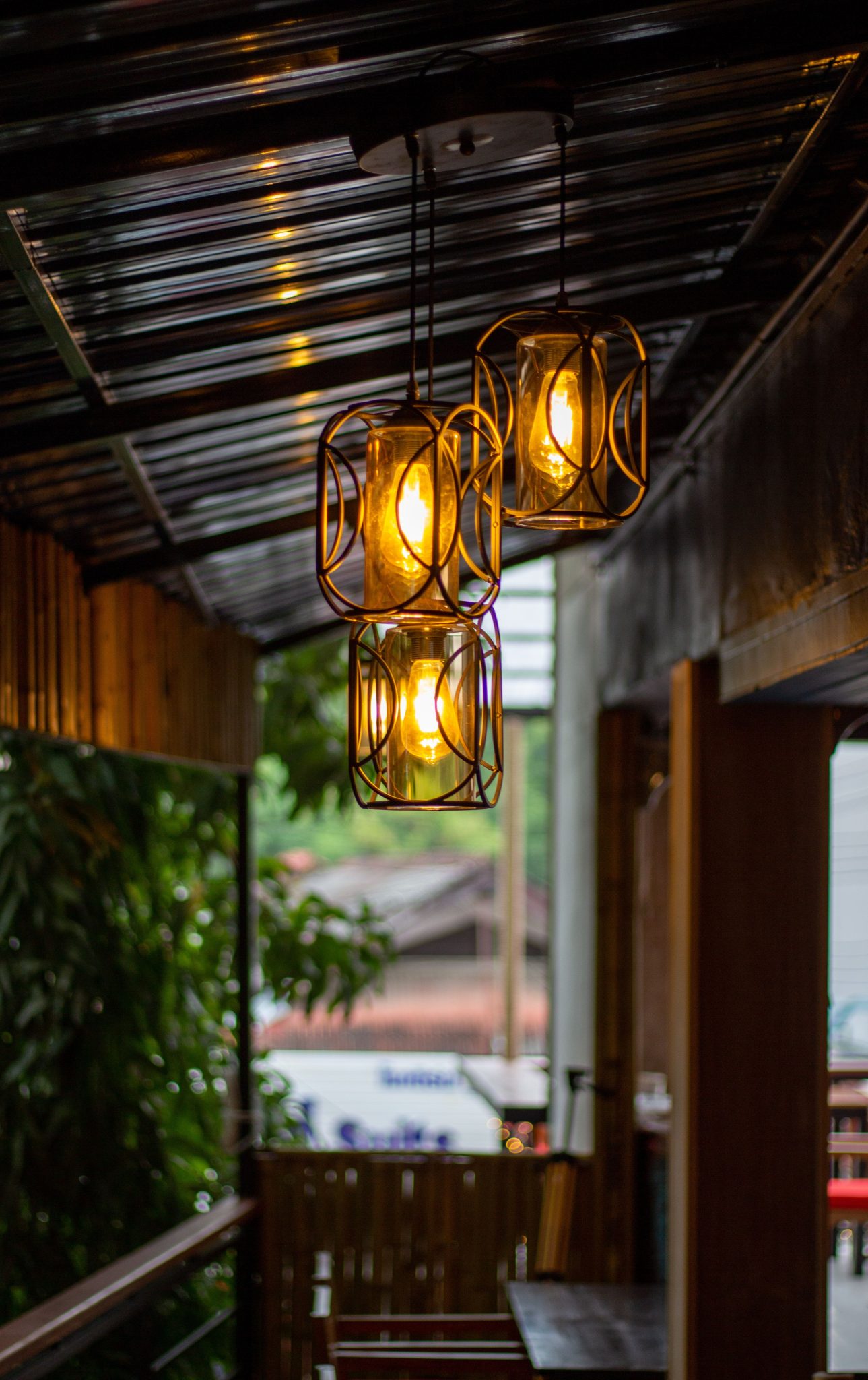 Charming outdoor lighting setup with three hanging lanterns on a covered porch, creating a warm ambiance.