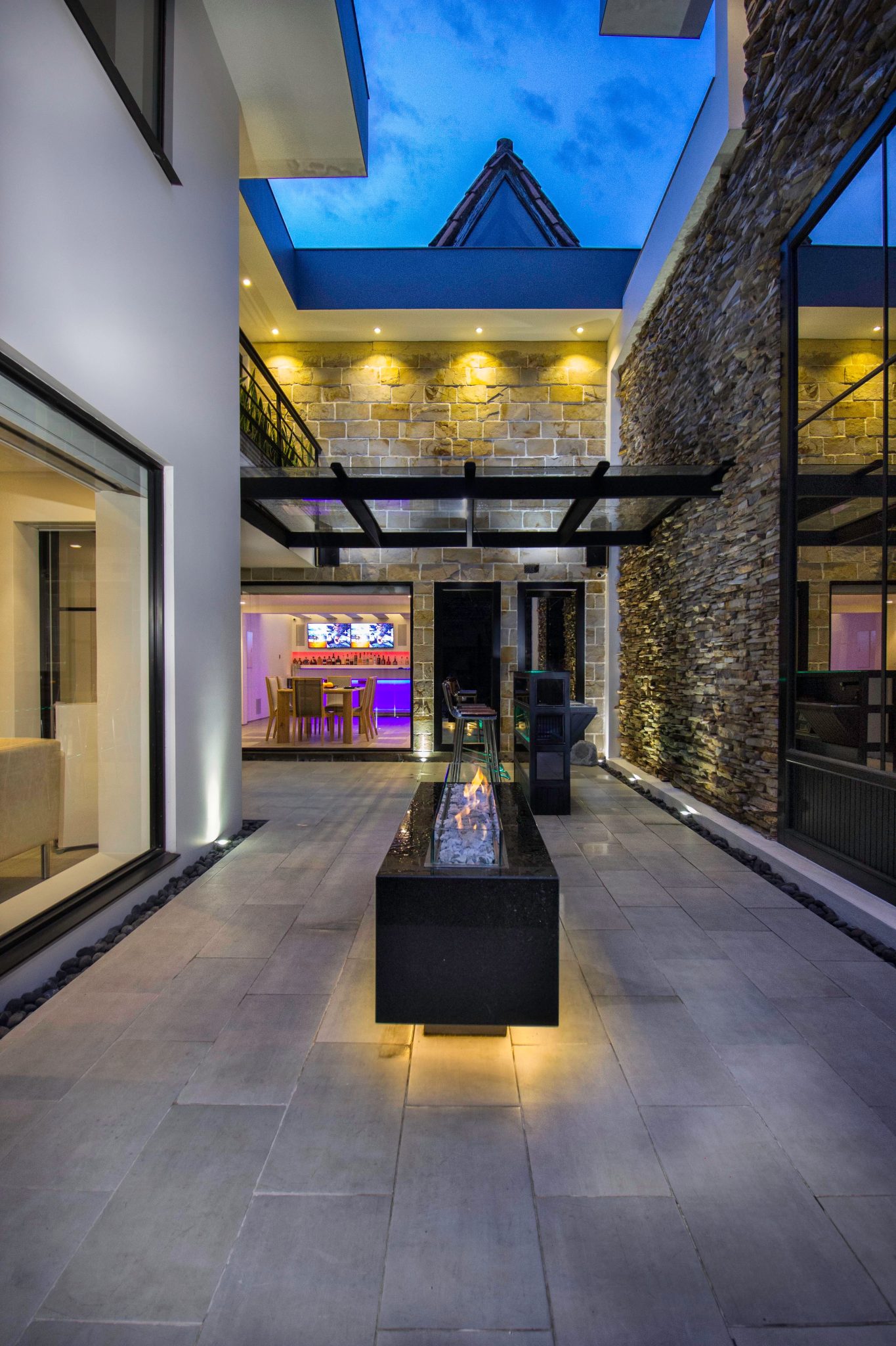 Contemporary outdoor patio featuring a sleek fire table and modern architecture at dusk.