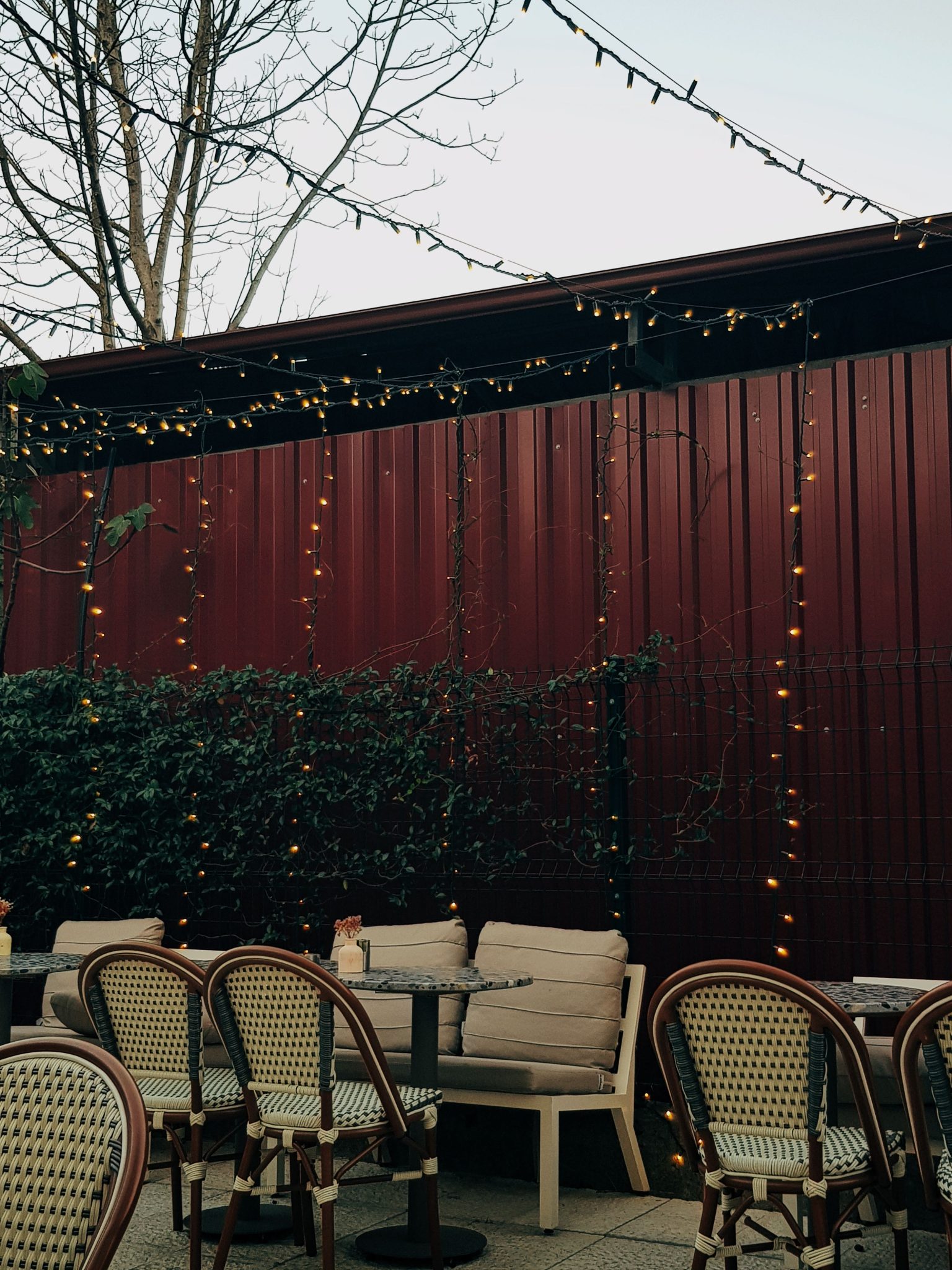 Cozy outdoor cafe setting with twinkling string lights, perfect for a relaxing evening.