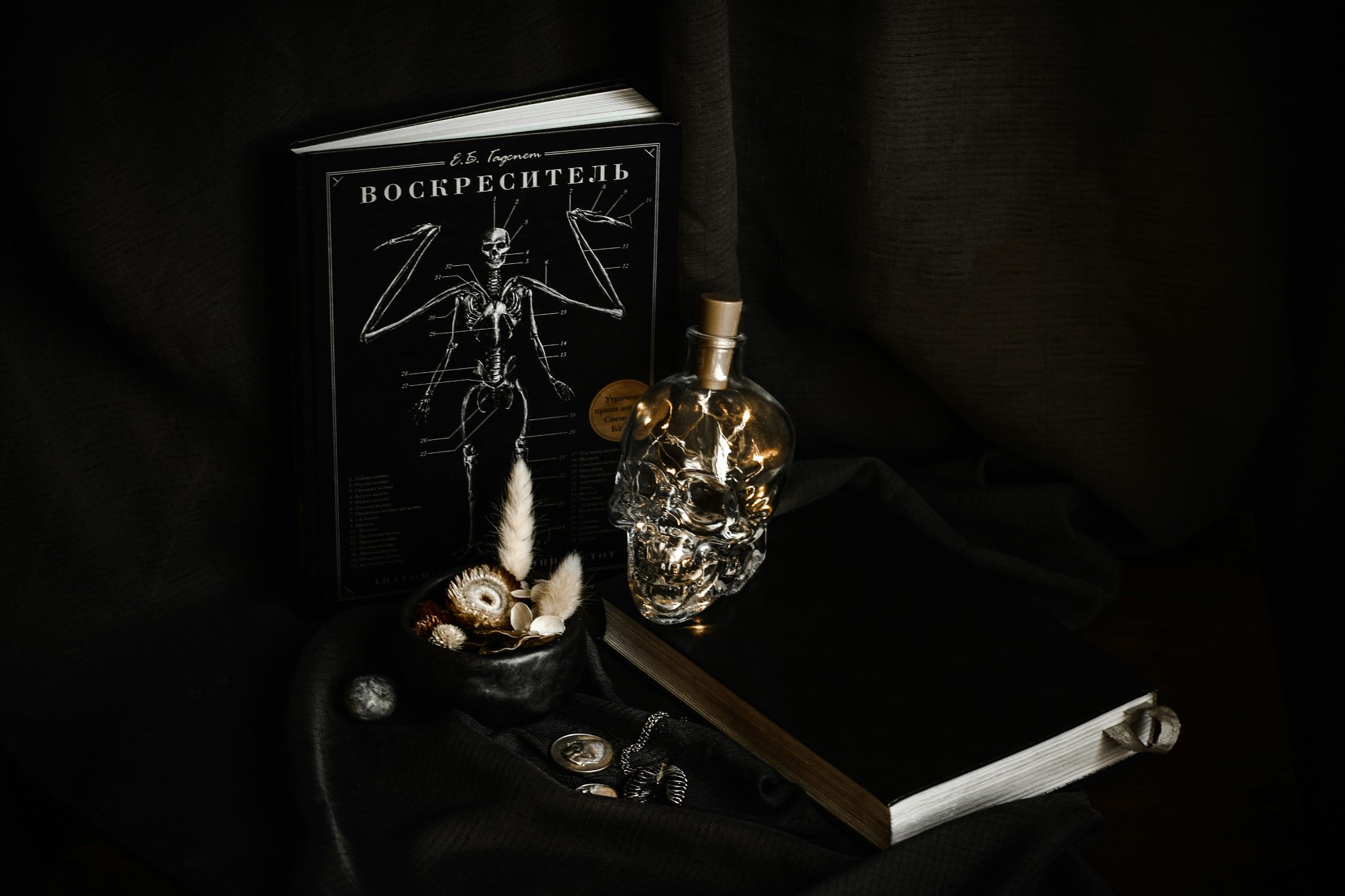 Dark still life with skull bottle and books