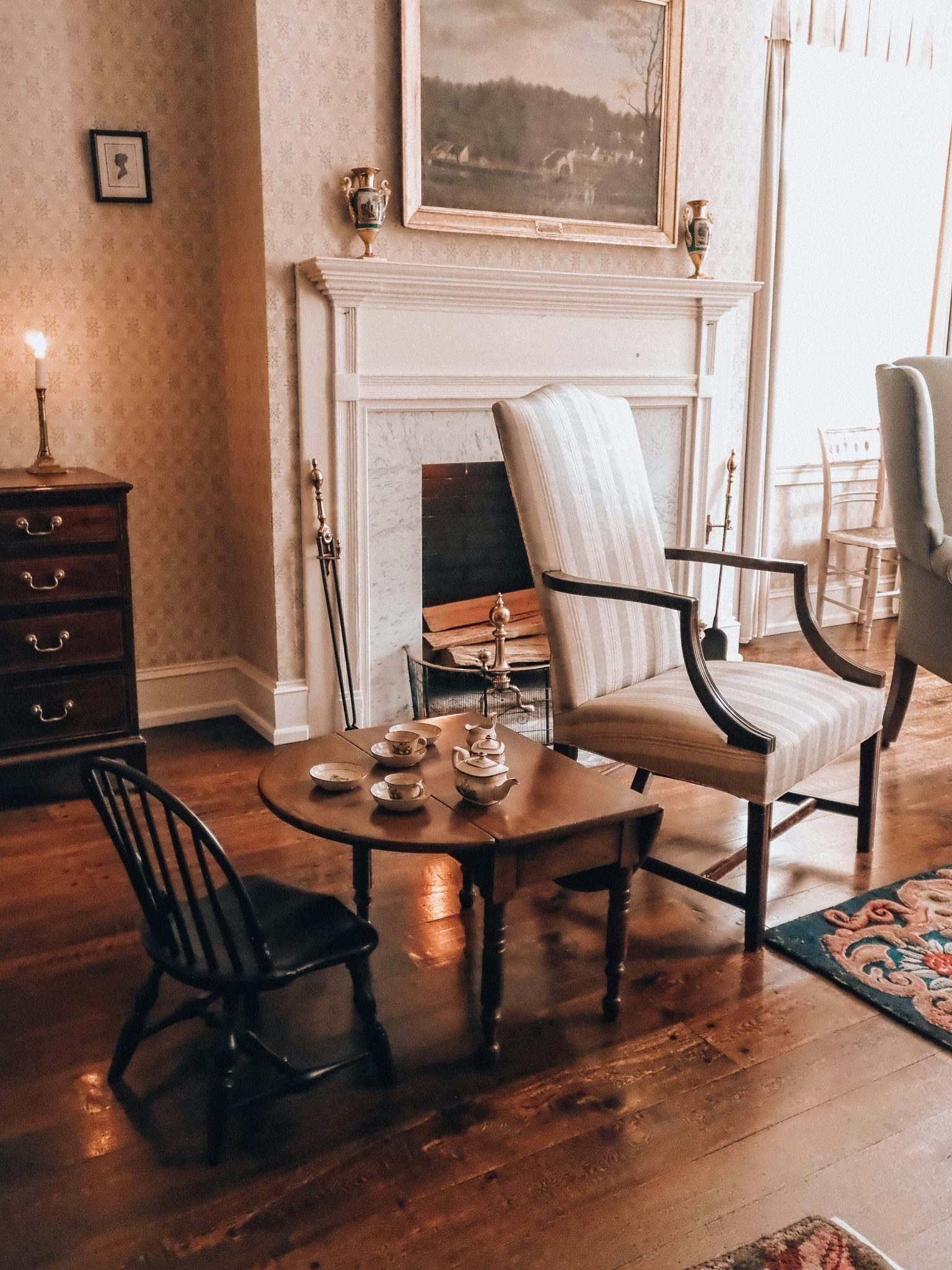 Elegant antique parlor with fireplace, chairs, and tea set