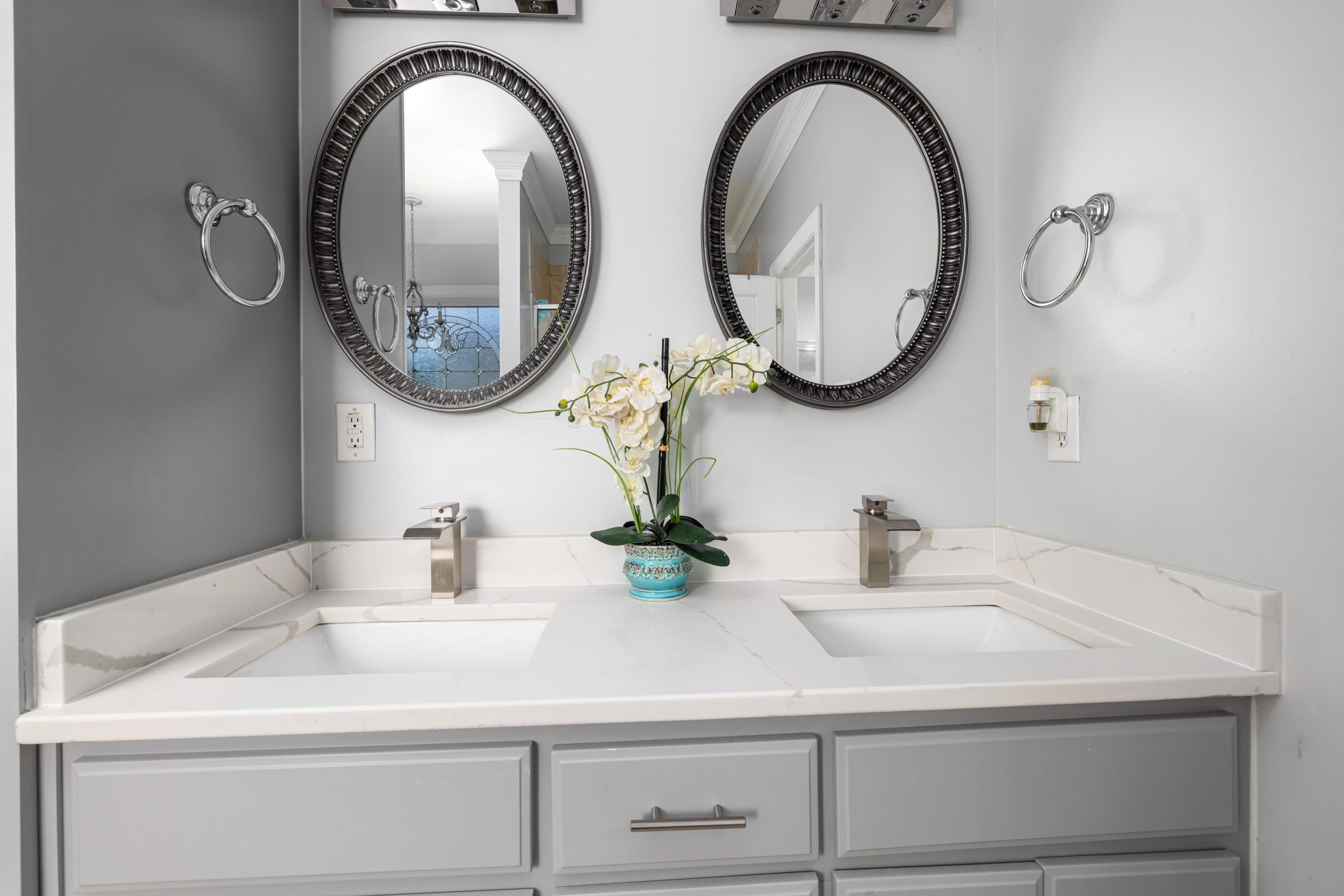 Elegant bathroom with dual sinks, mirrors, and a marble countertop featuring contemporary fixtures.