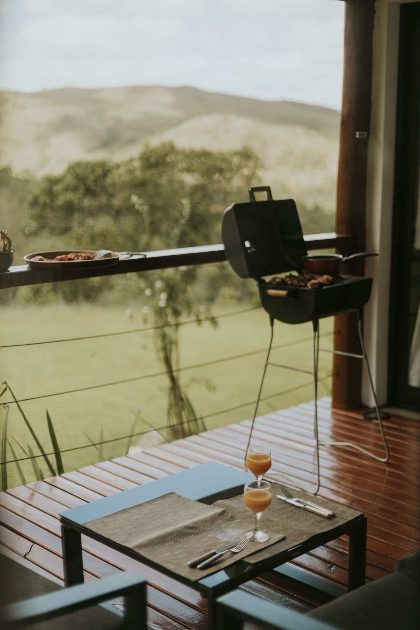 Enjoy a serene barbecue on a wooden deck overlooking a lush landscape.