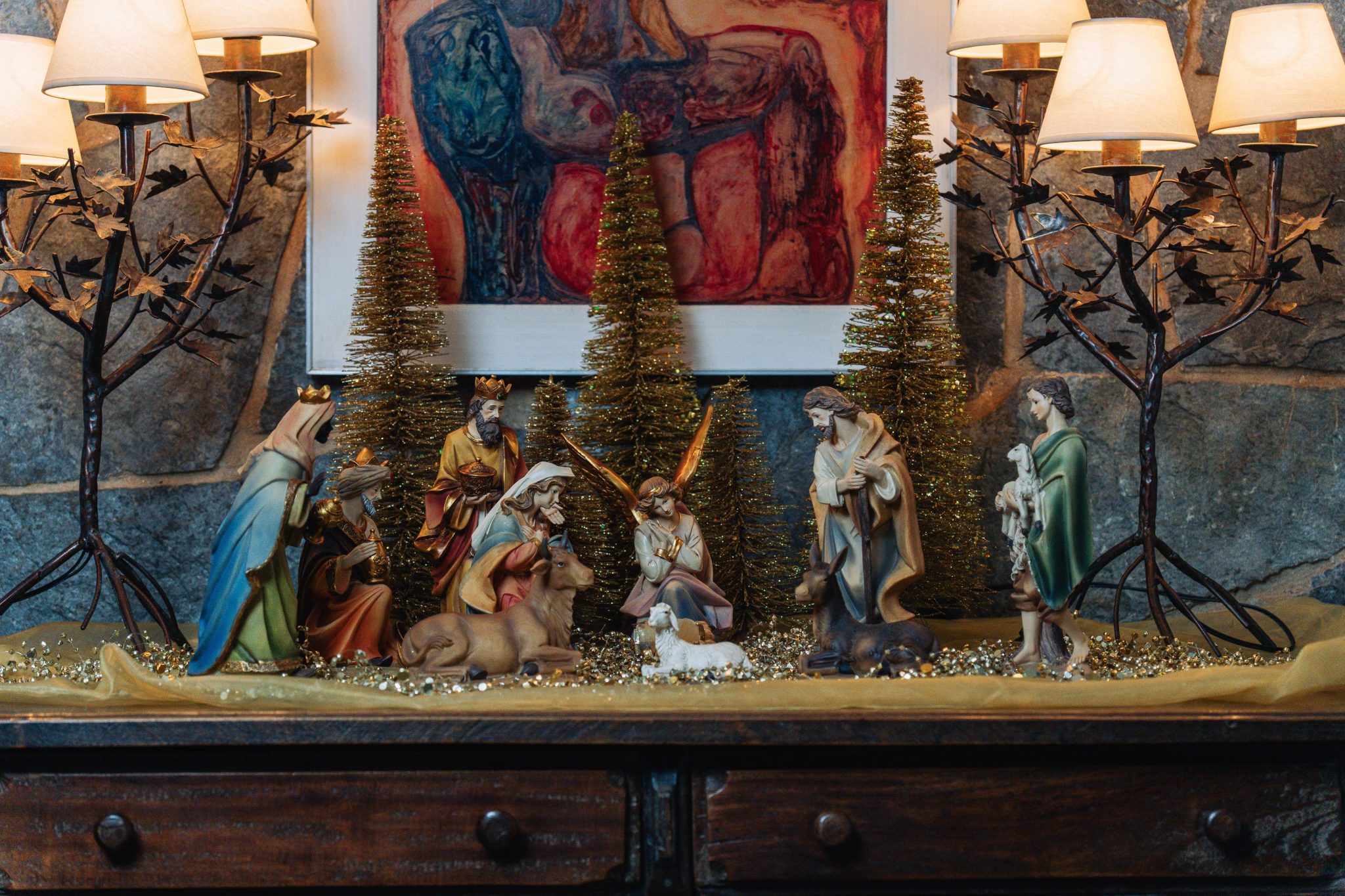 Festive Christmas nativity scene with figurines and warm lighting indoors creating a cozy holiday atmosphere.