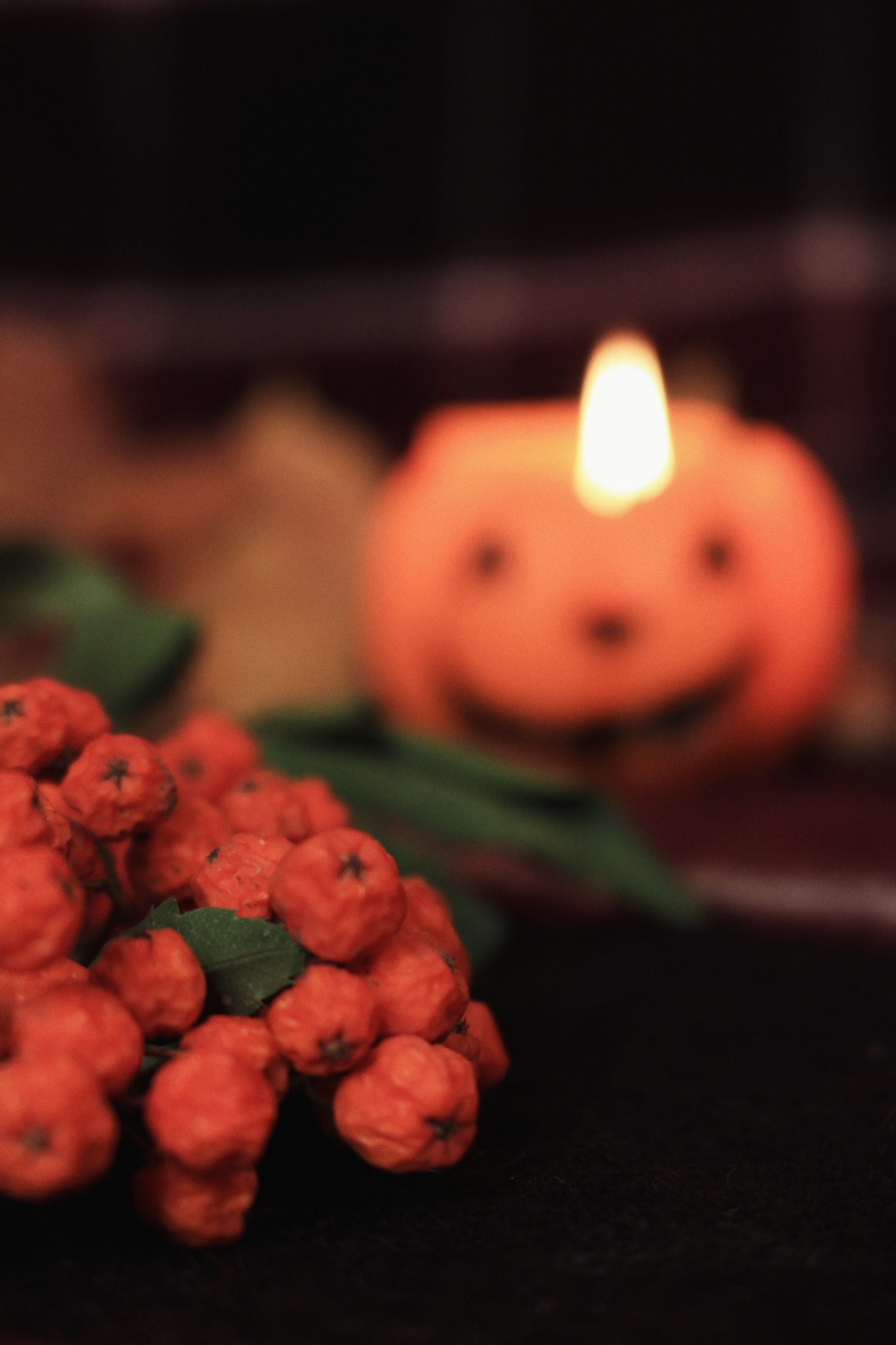 Festive Halloween scene with a glowing pumpkin candle and decorative berries.