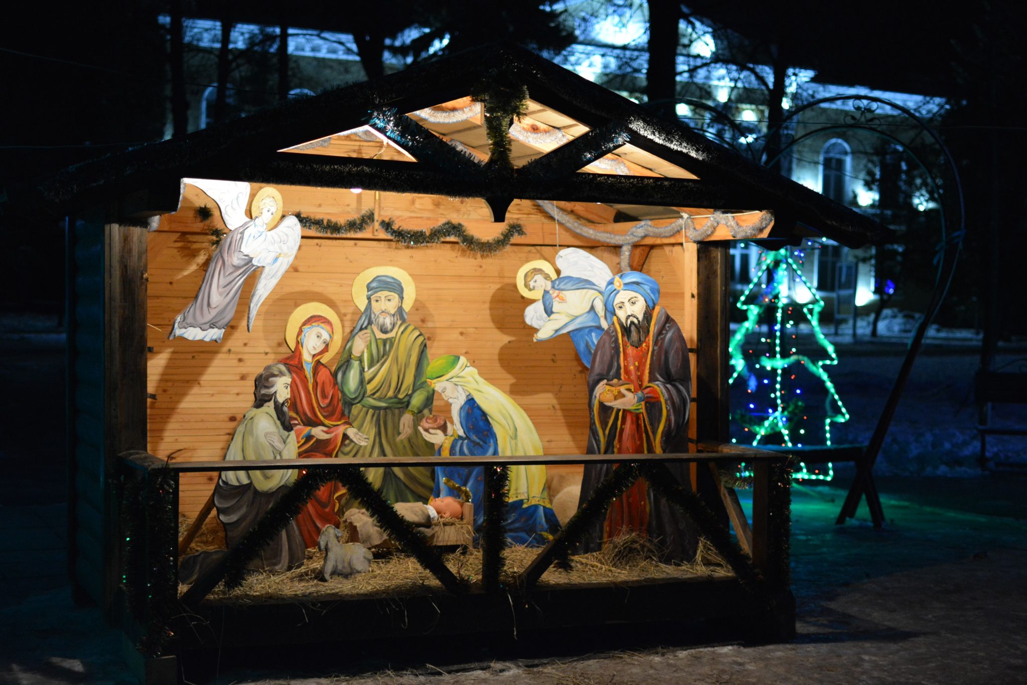 Illuminated nativity scene depicting Jesus' birth with vibrant Christmas lights.