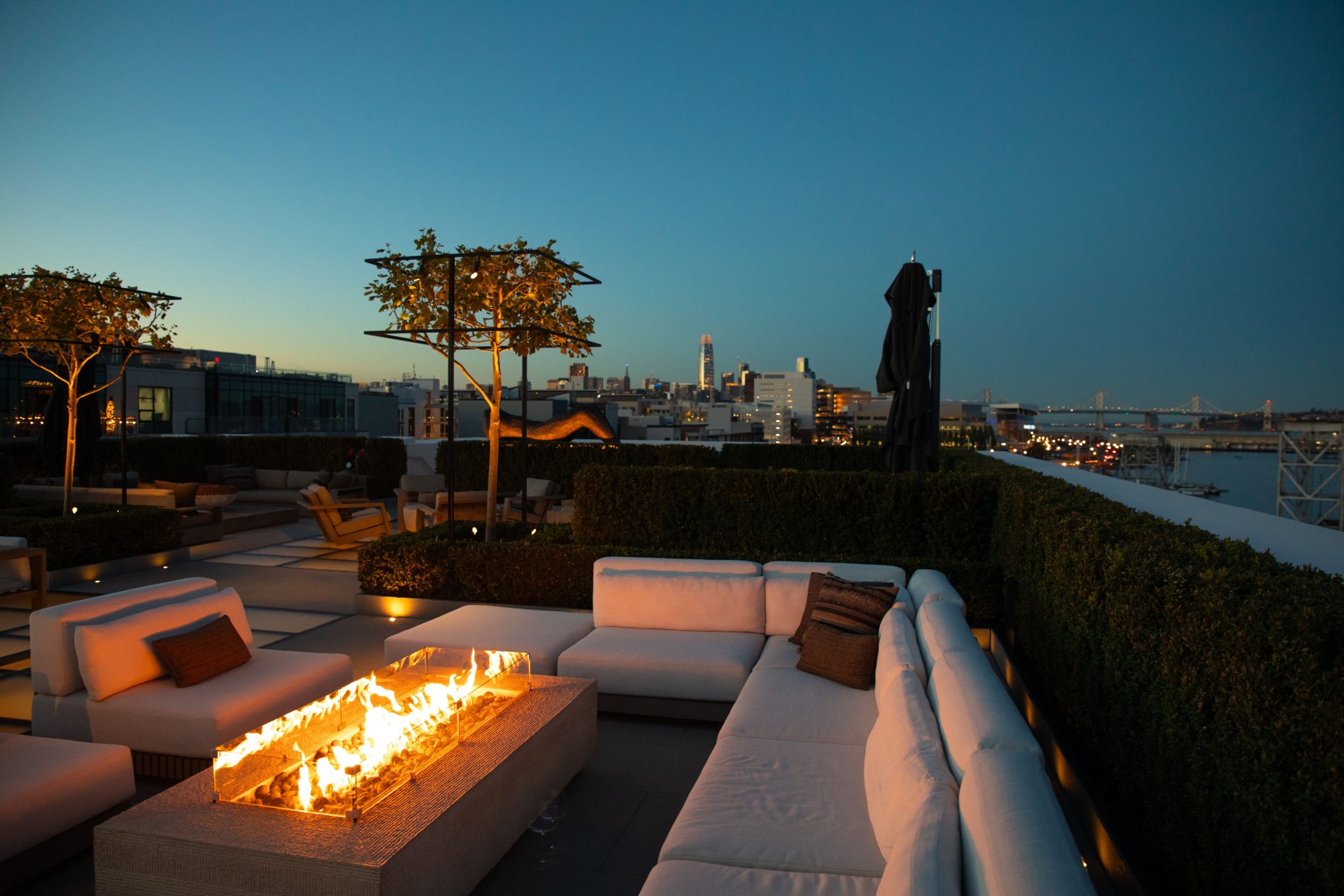 Luxury rooftop terrace in San Francisco with a fire pit and stunning cityscape view at dusk.