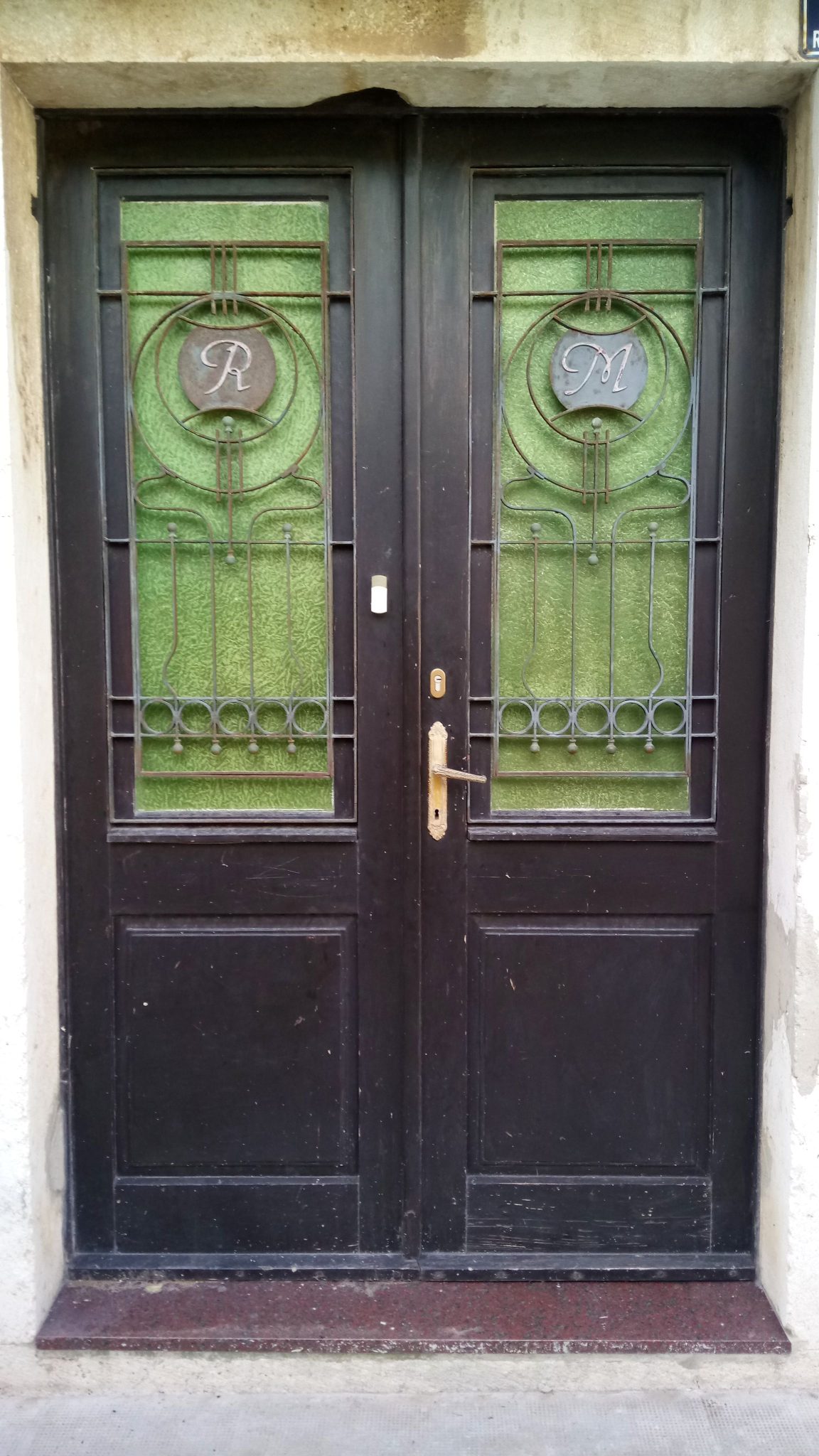 Ornate wooden door featuring green stained glass panels with artistic metalwork.