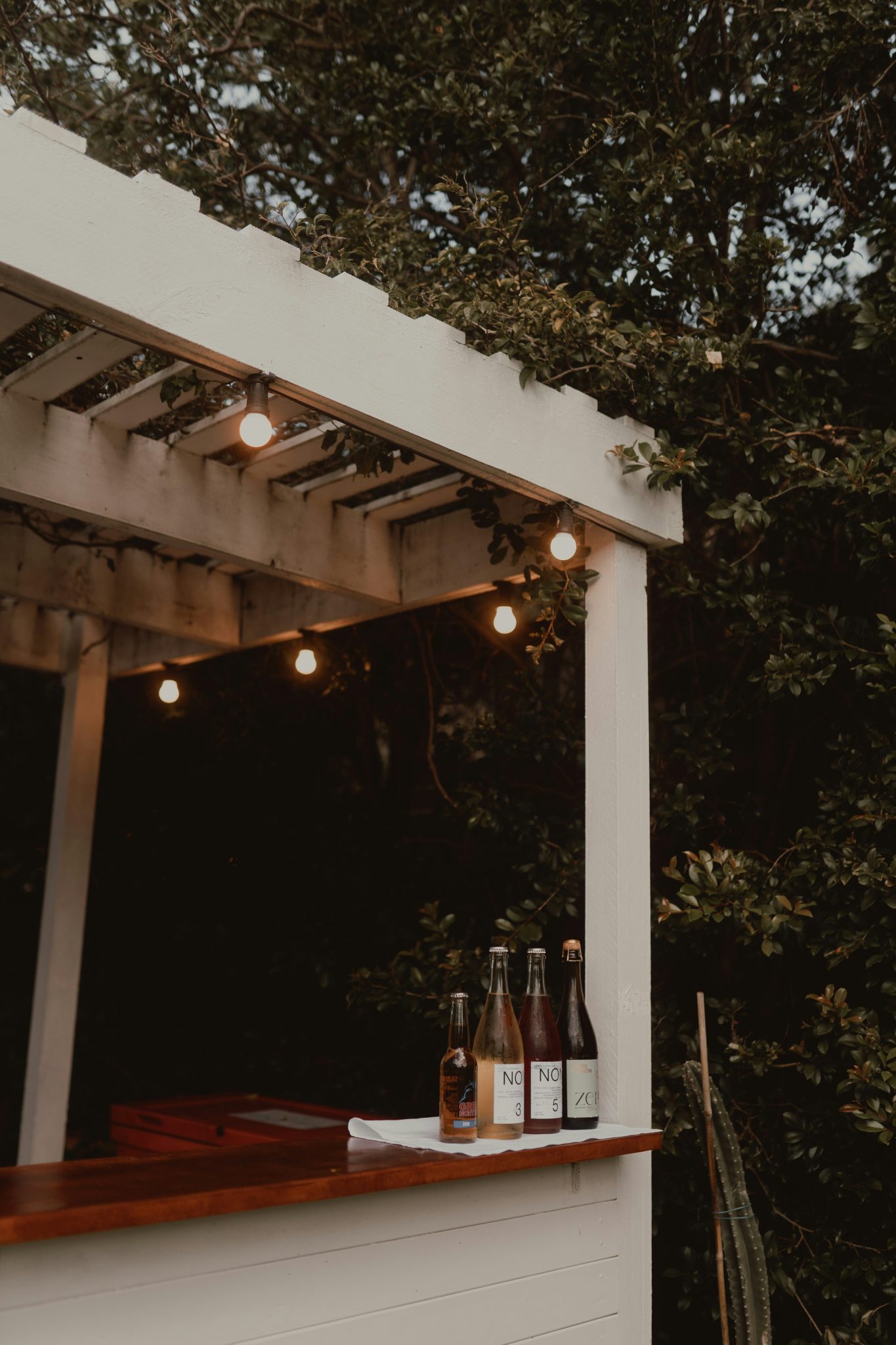 Outdoor bar with string lights and bottles at dusk