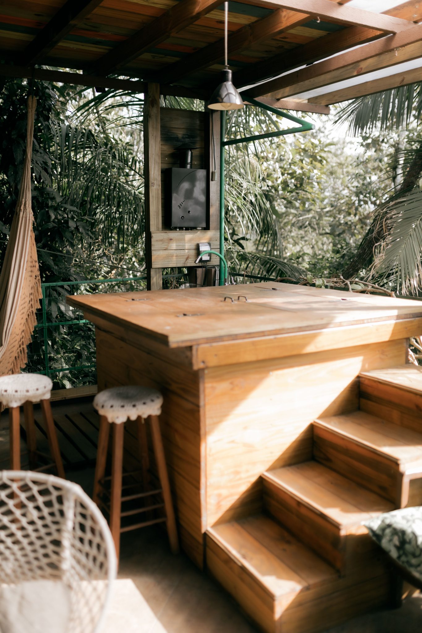 Relaxing tropical outdoor patio with wooden bar and stools, perfect for leisure.