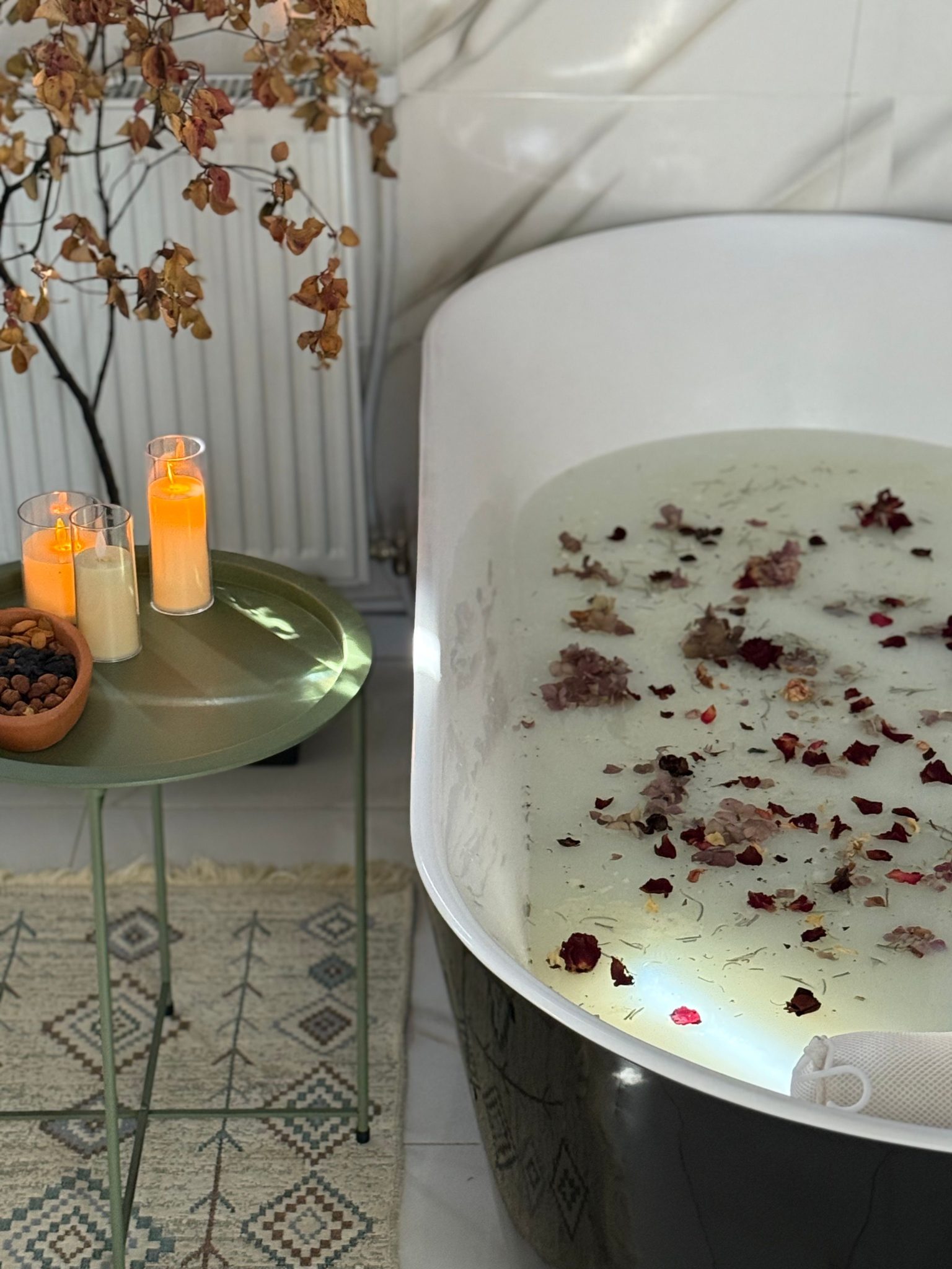 Serene bathtub filled with petals and lit candles, perfect for relaxation.