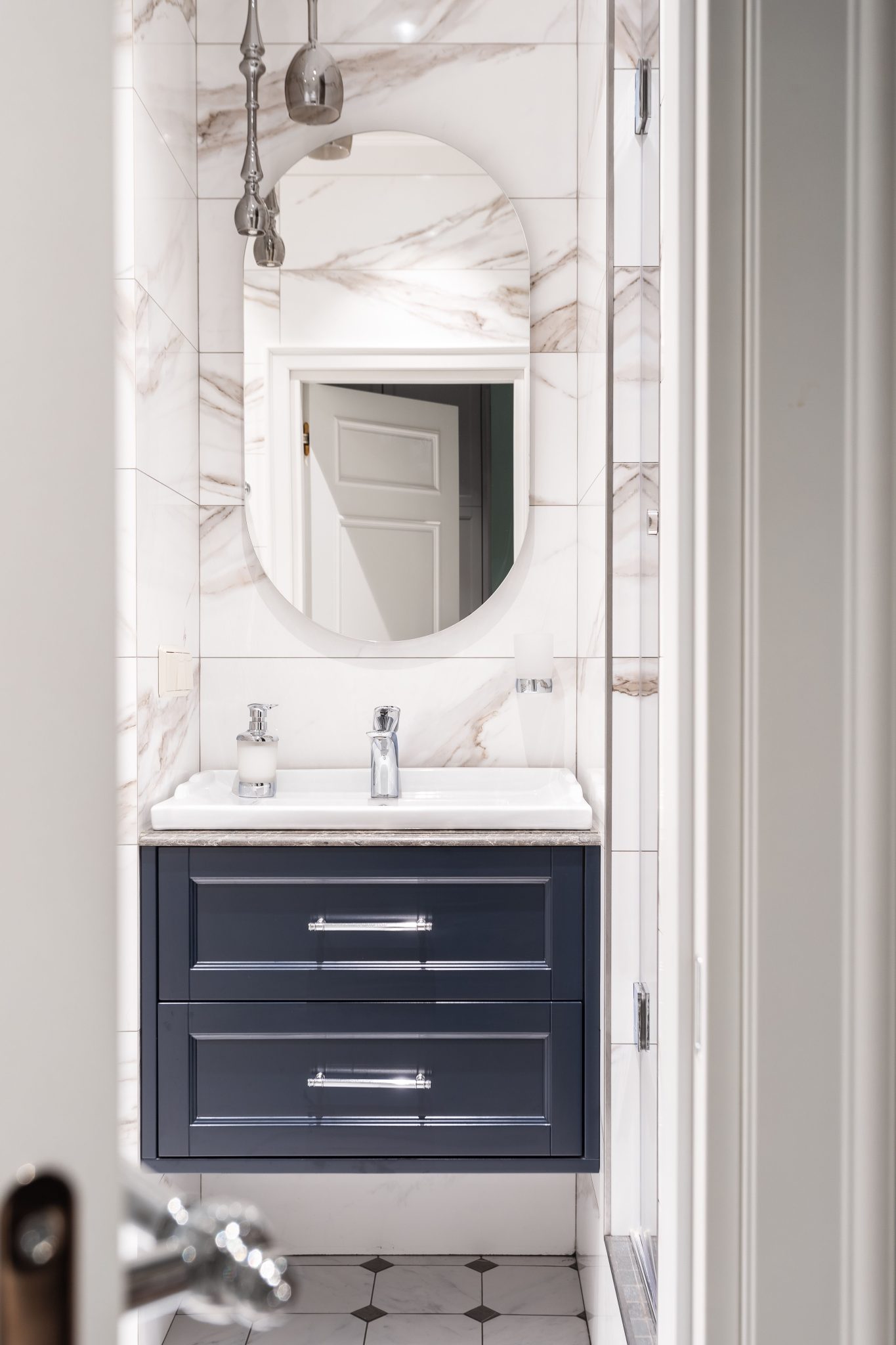 Sleek bathroom with marble tiles and stylish round mirror in Saint Petersburg.