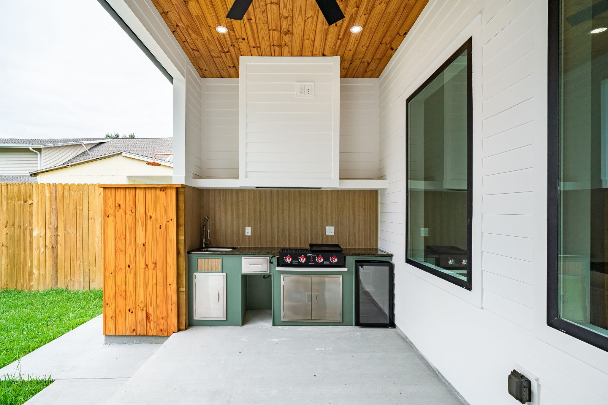 Sleek outdoor kitchen setup with BBQ and fridge in New Orleans backyard.