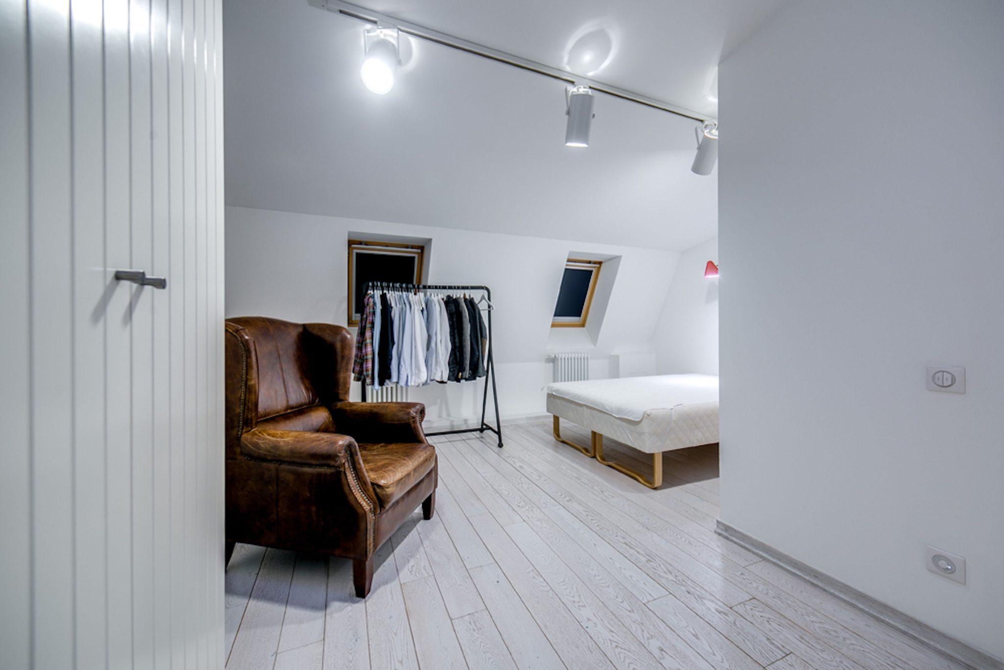 Spacious modern bedroom featuring leather armchair and sleek bed design.