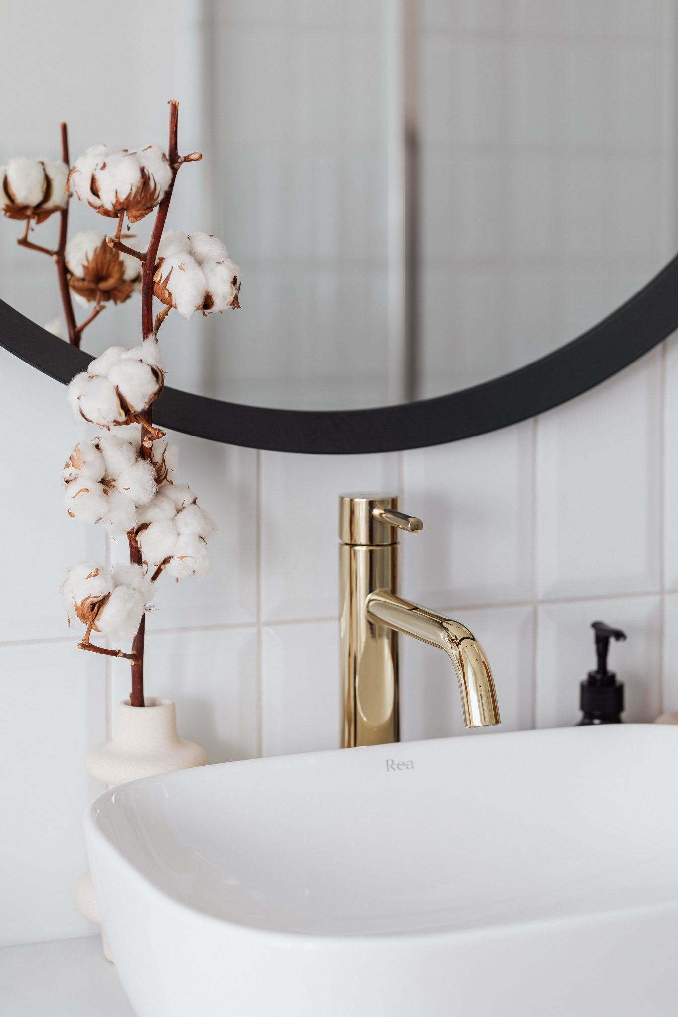 Stylish bathroom featuring a sleek golden faucet and cotton plant decoration.