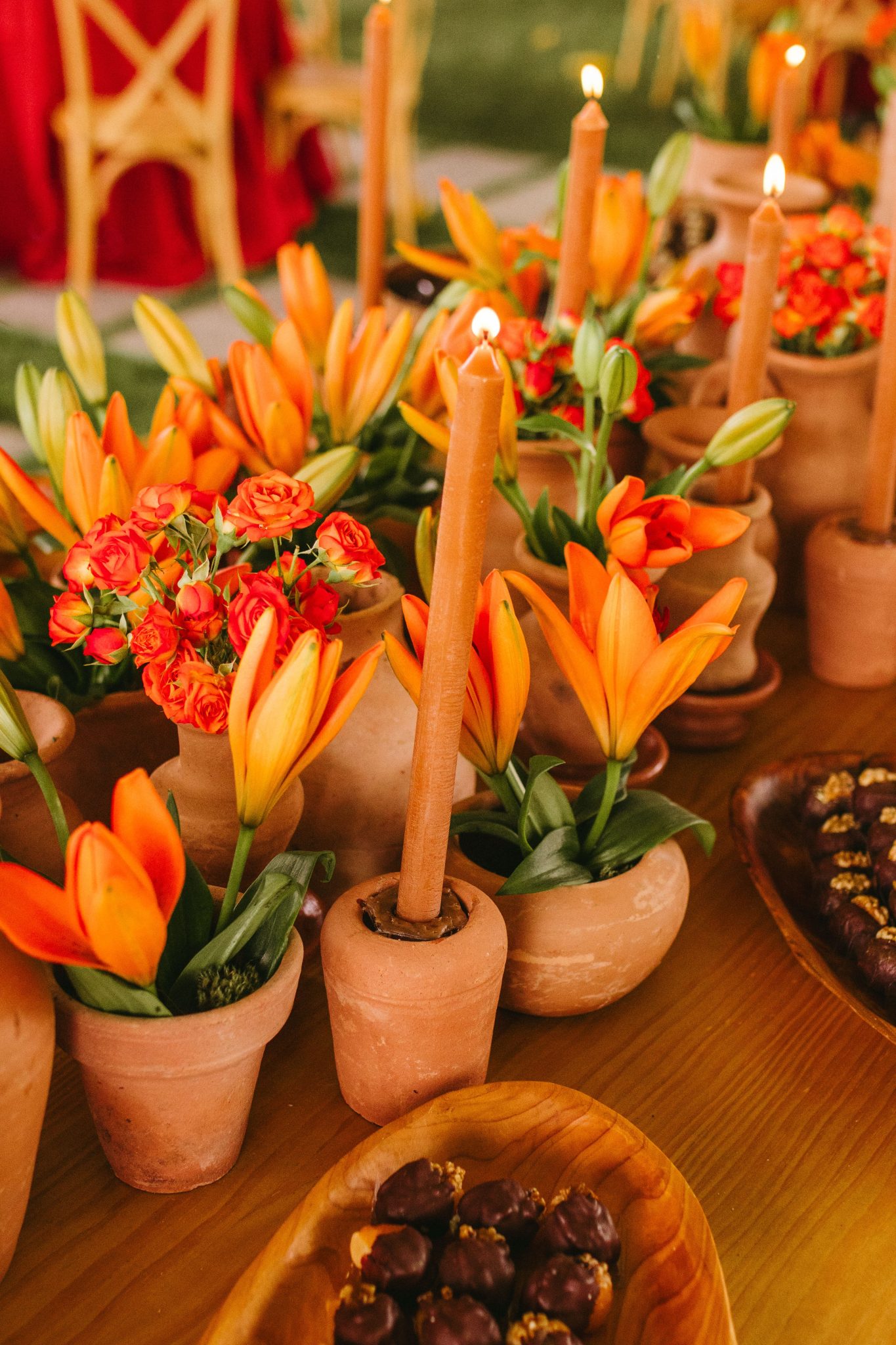 Terracotta pots with orange flowers and candles create a warm wedding ambiance.