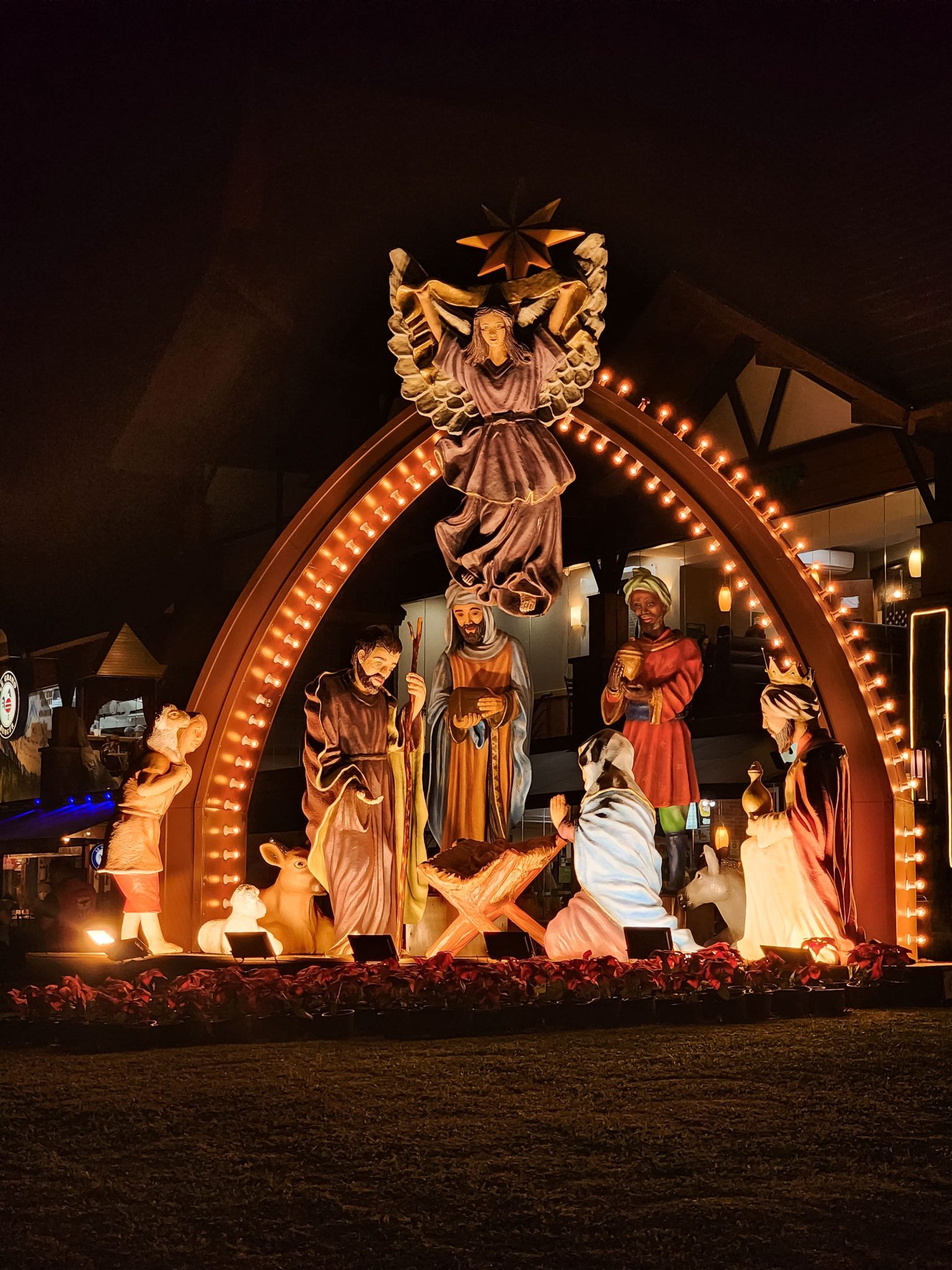 Vibrantly lit nativity scene depicting the birth of Jesus, captured at night.