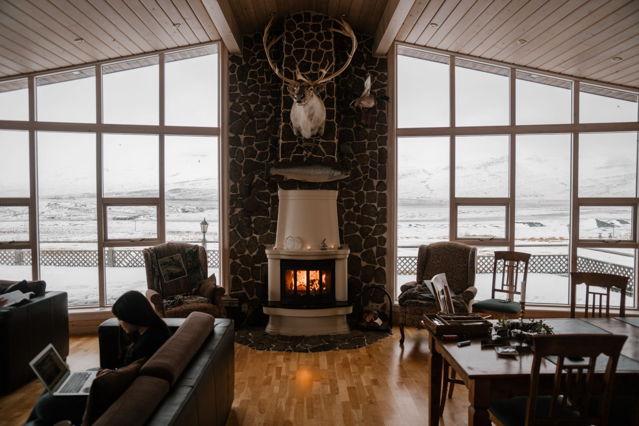 Warm and inviting living room with a fireplace and large windows overlooking snow-covered mountains.
