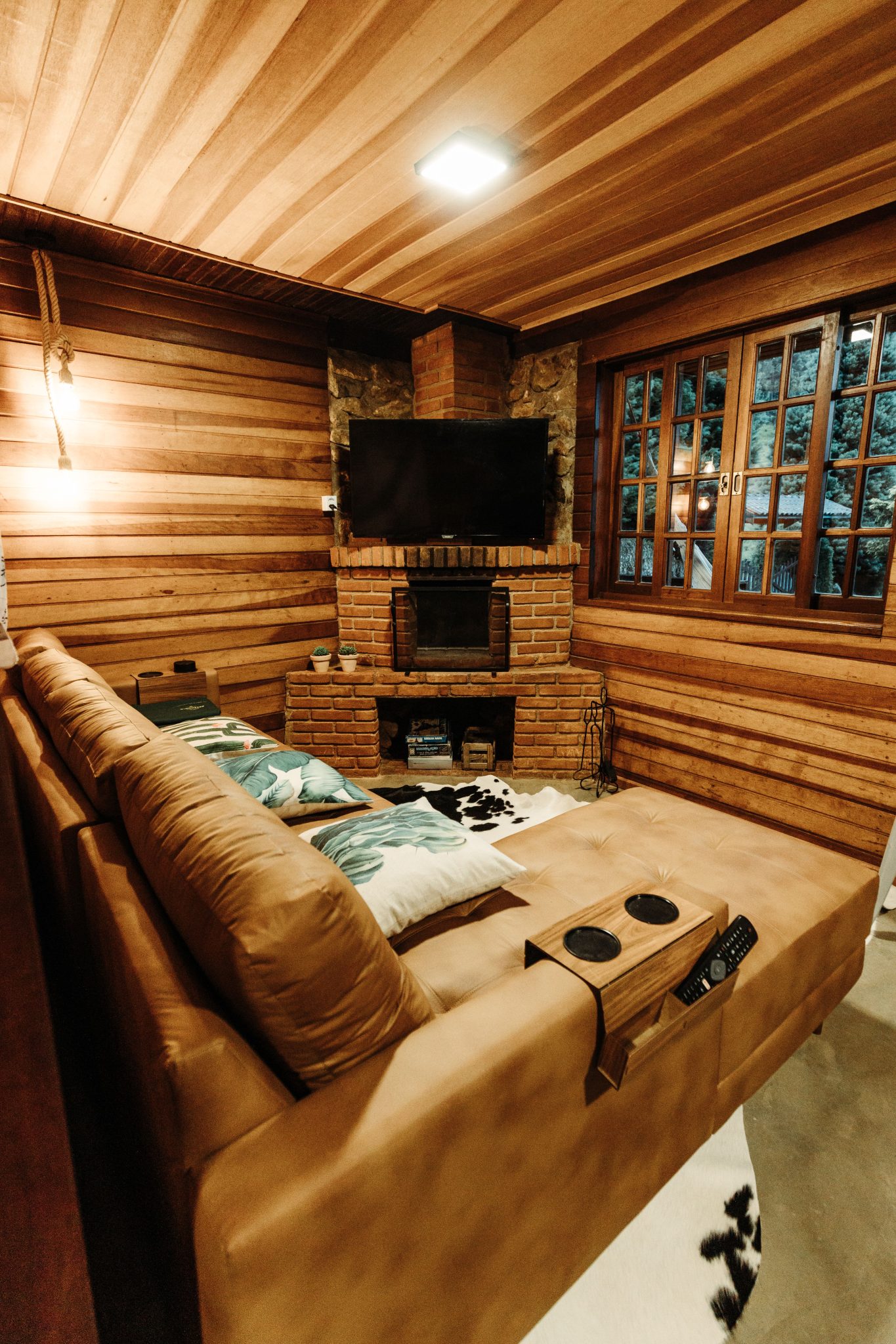 Warm and inviting rustic living room featuring a wooden interior, stone fireplace, and comfortable sofa.