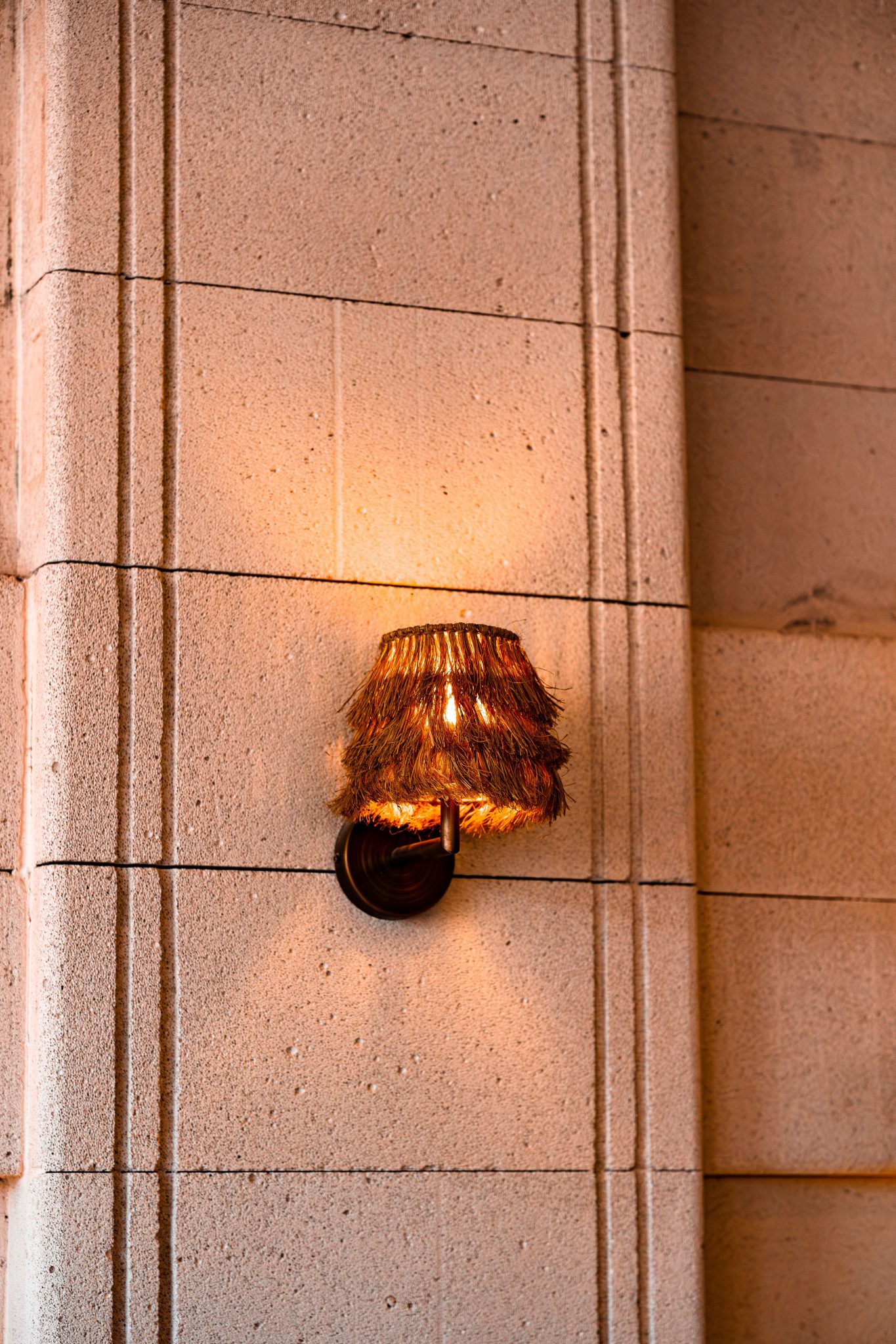 Warm glowing rustic wall sconce on textured stone wall in Yalova, Türkiye.
