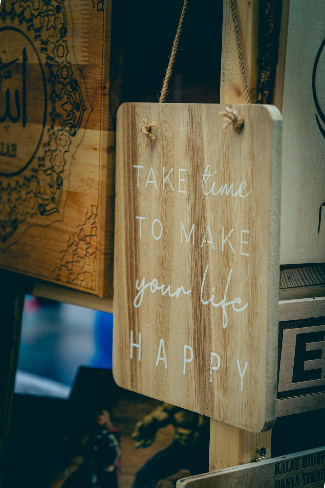 Wooden board with motivational text to uplift spirits and encourage happiness.