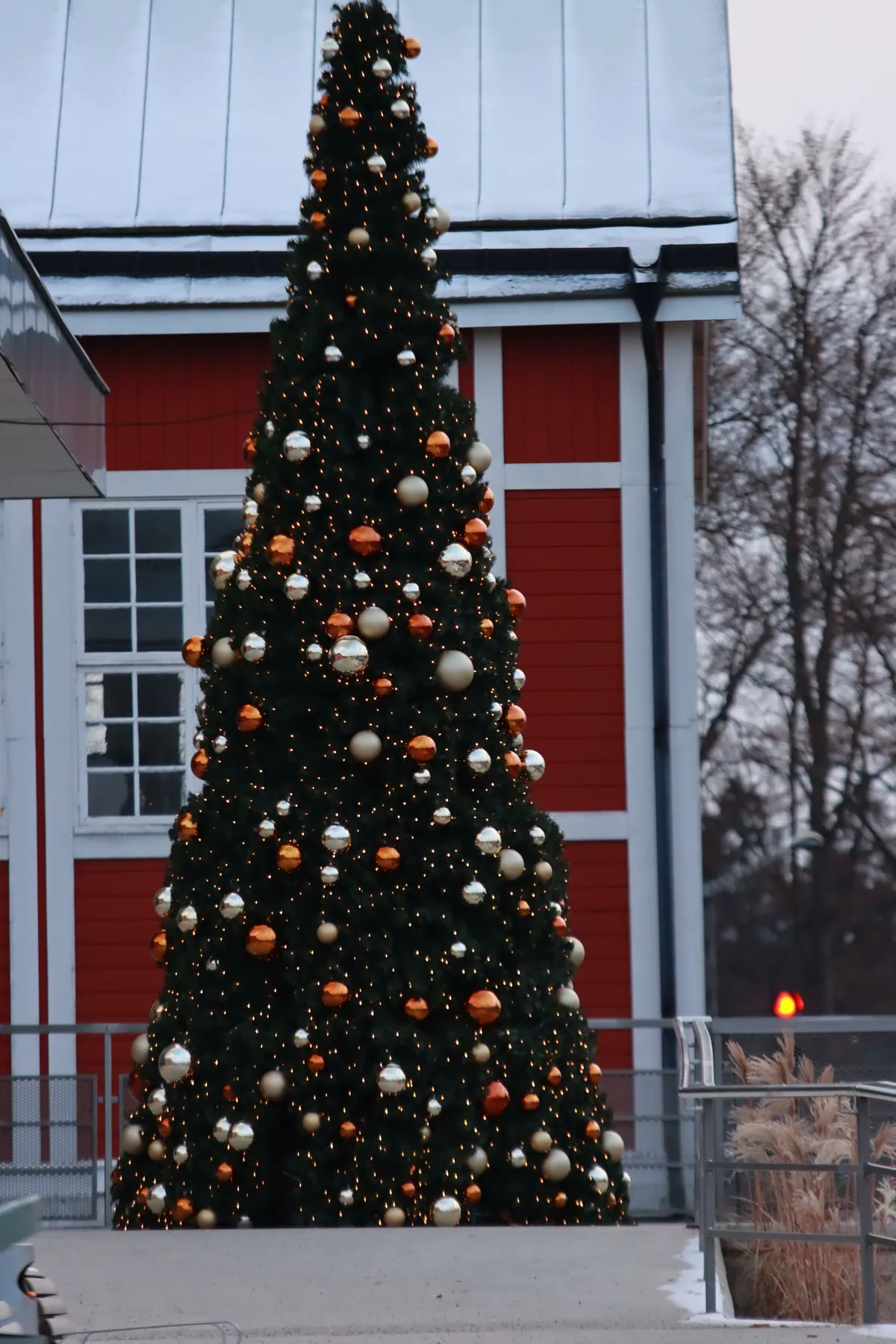 A beautifully decorated Christmas tree set outdoors near a charming red house in Sweden.