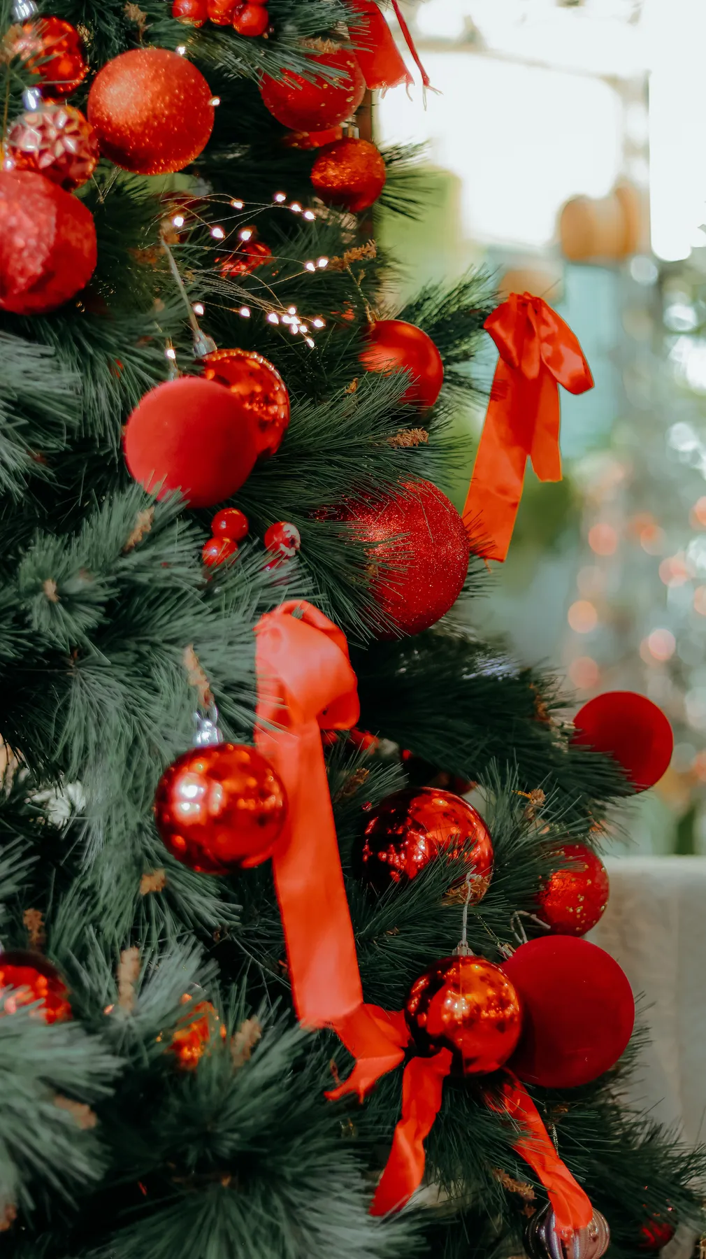 A Christmas tree adorned with vibrant red baubles and bows, showcasing festive holiday spirit.